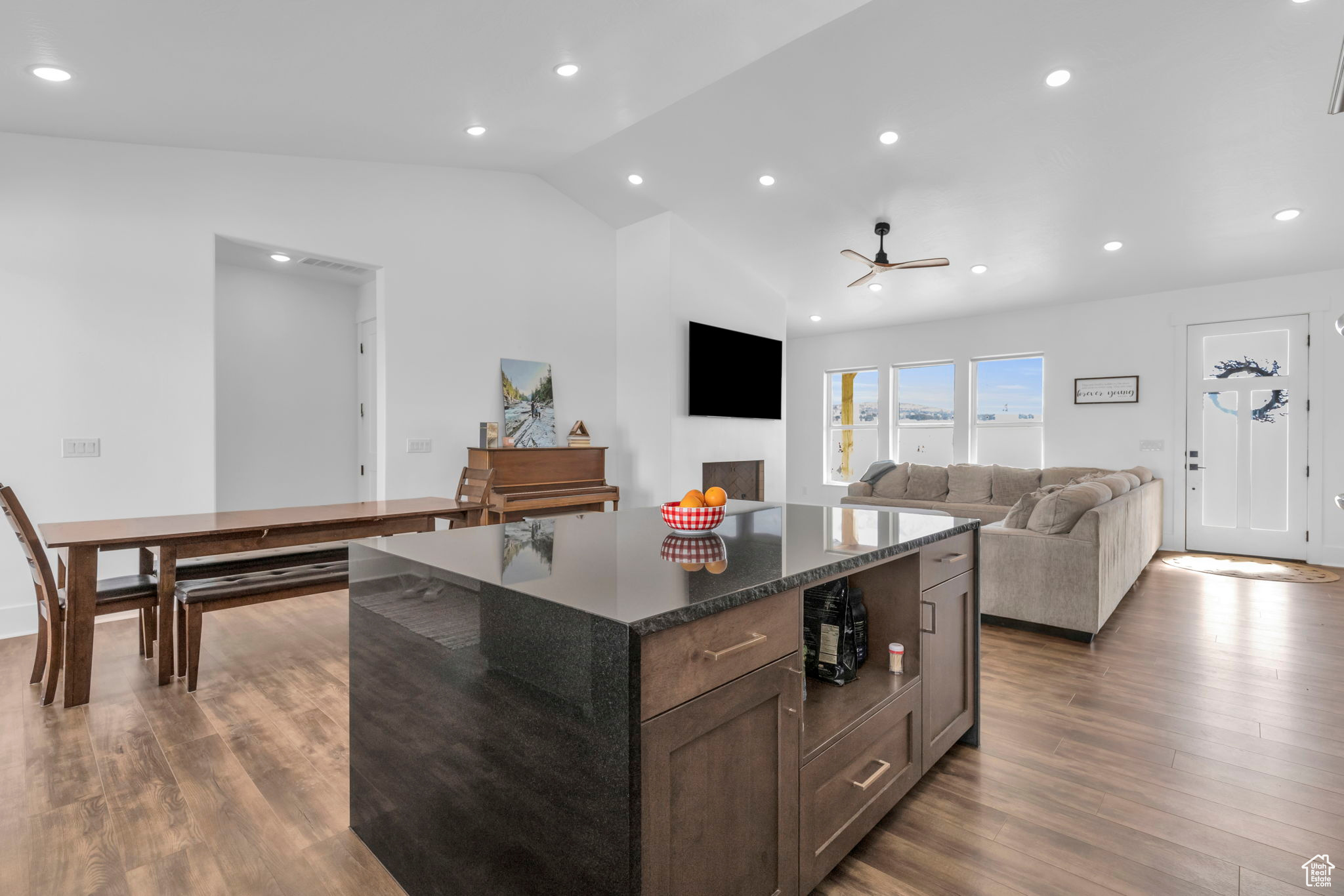 Kitchen featuring dark stone counters, a kitchen island, lofted ceiling, dark hardwood / wood-style floors, and ceiling fan