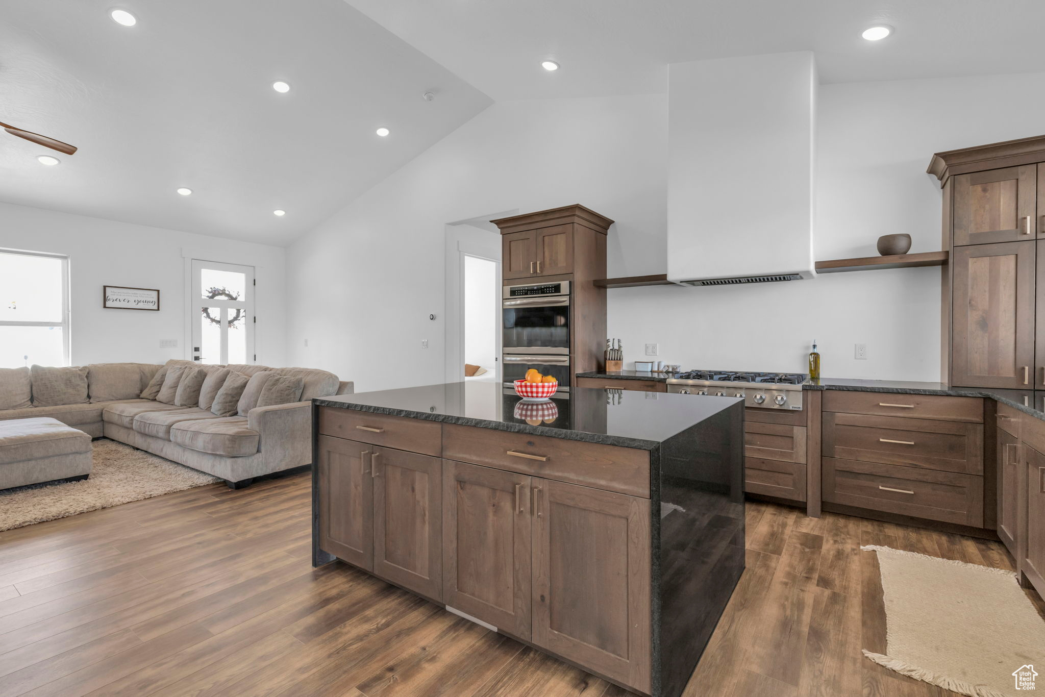 Kitchen with dark stone counters, appliances with stainless steel finishes, dark hardwood / wood-style floors, a center island, and ceiling fan