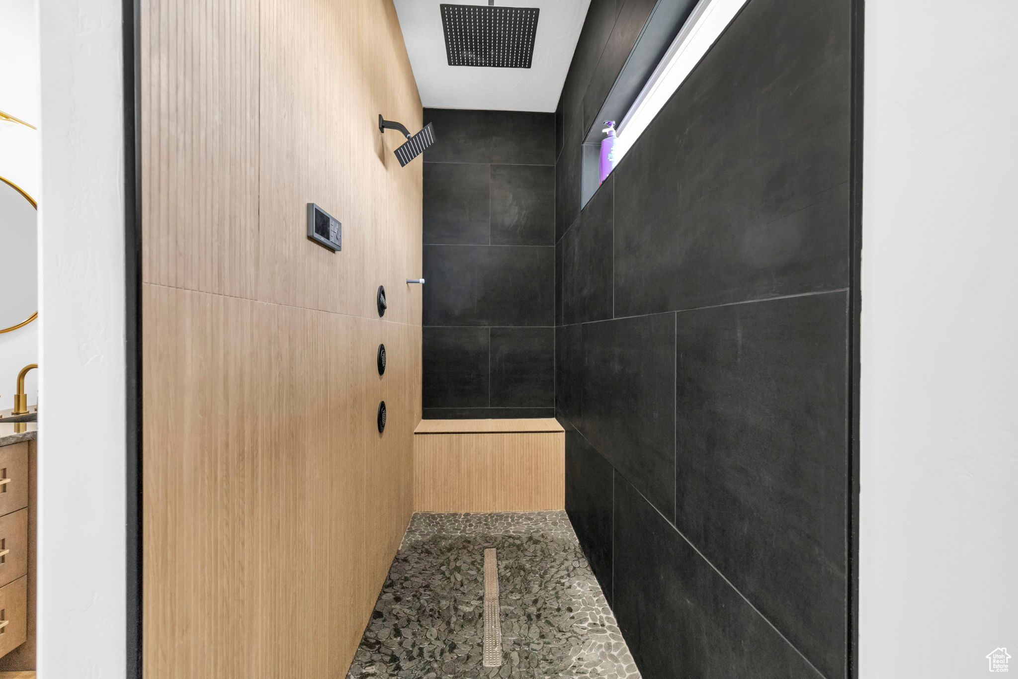 Bathroom featuring a shower and tile walls