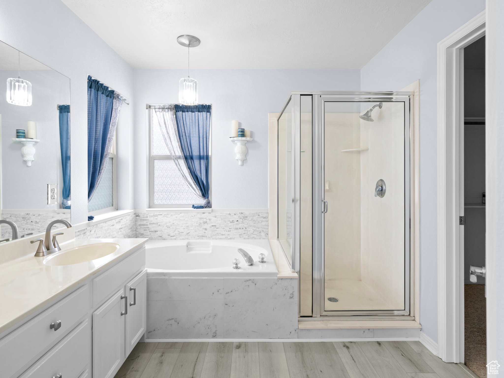 Bathroom featuring hardwood / wood-style floors, plus walk in shower, and vanity with extensive cabinet space