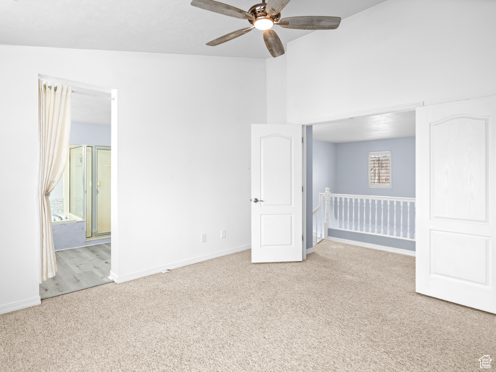 Unfurnished room featuring a wealth of natural light, ceiling fan, light colored carpet, and vaulted ceiling