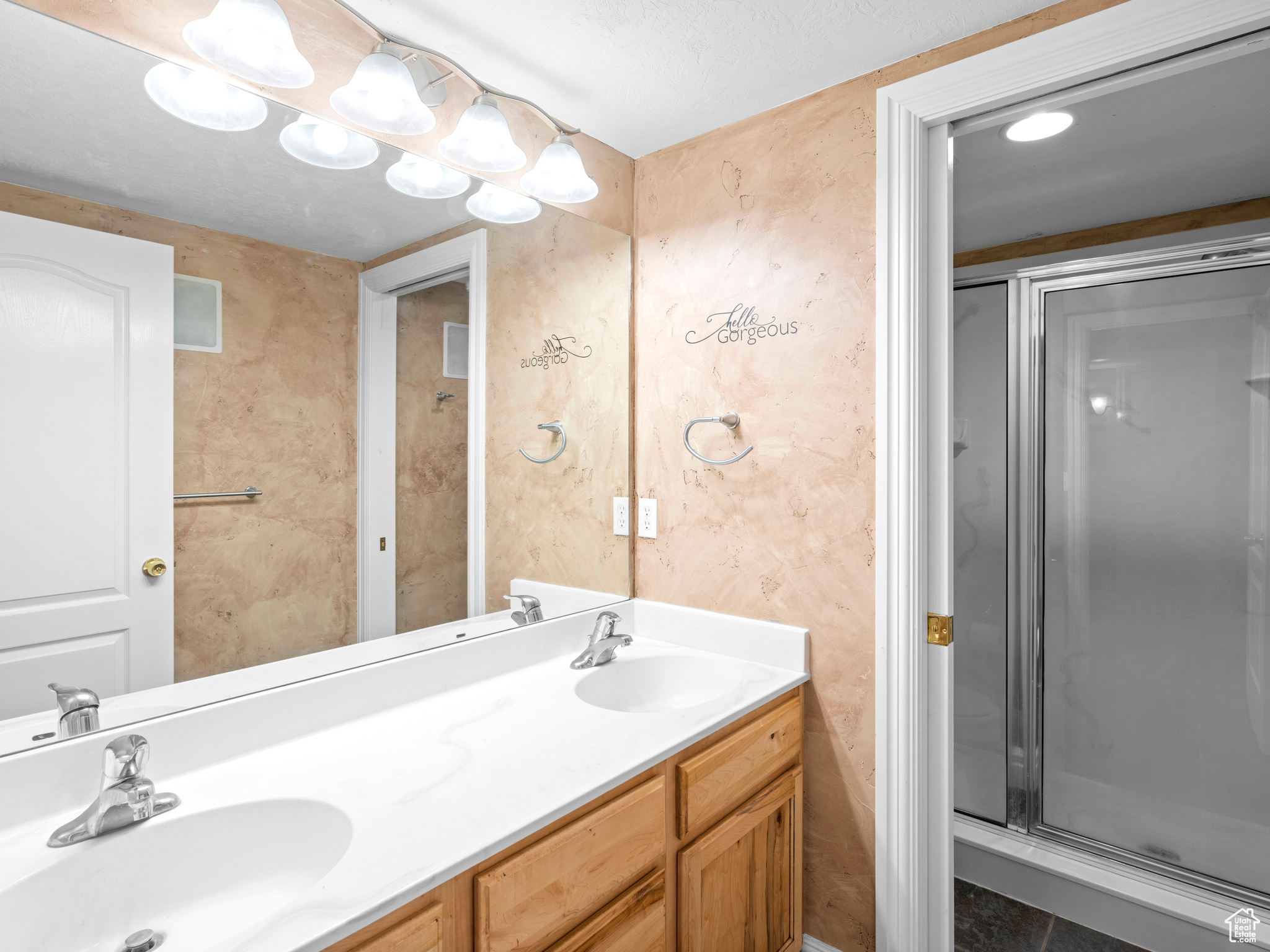 Bathroom with dual vanity, walk in shower, and tile flooring