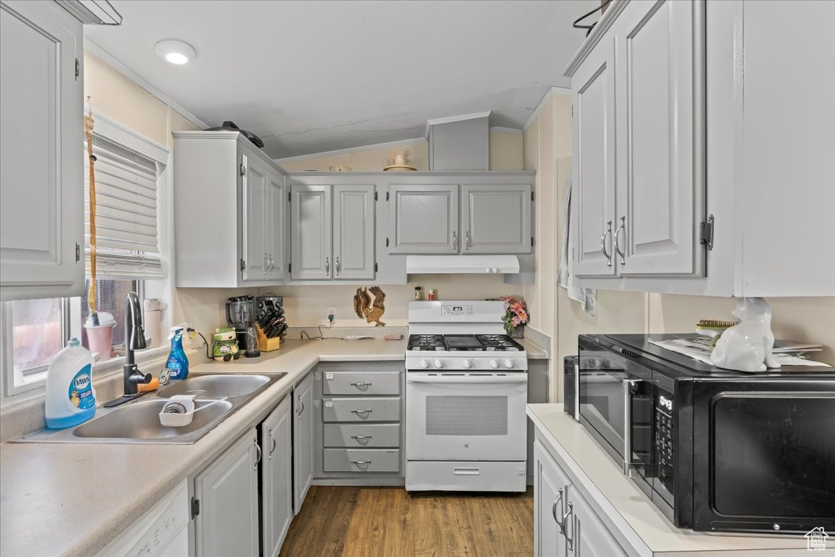 Kitchen with white cabinetry, white appliances, light hardwood / wood-style floors, lofted ceiling, and sink