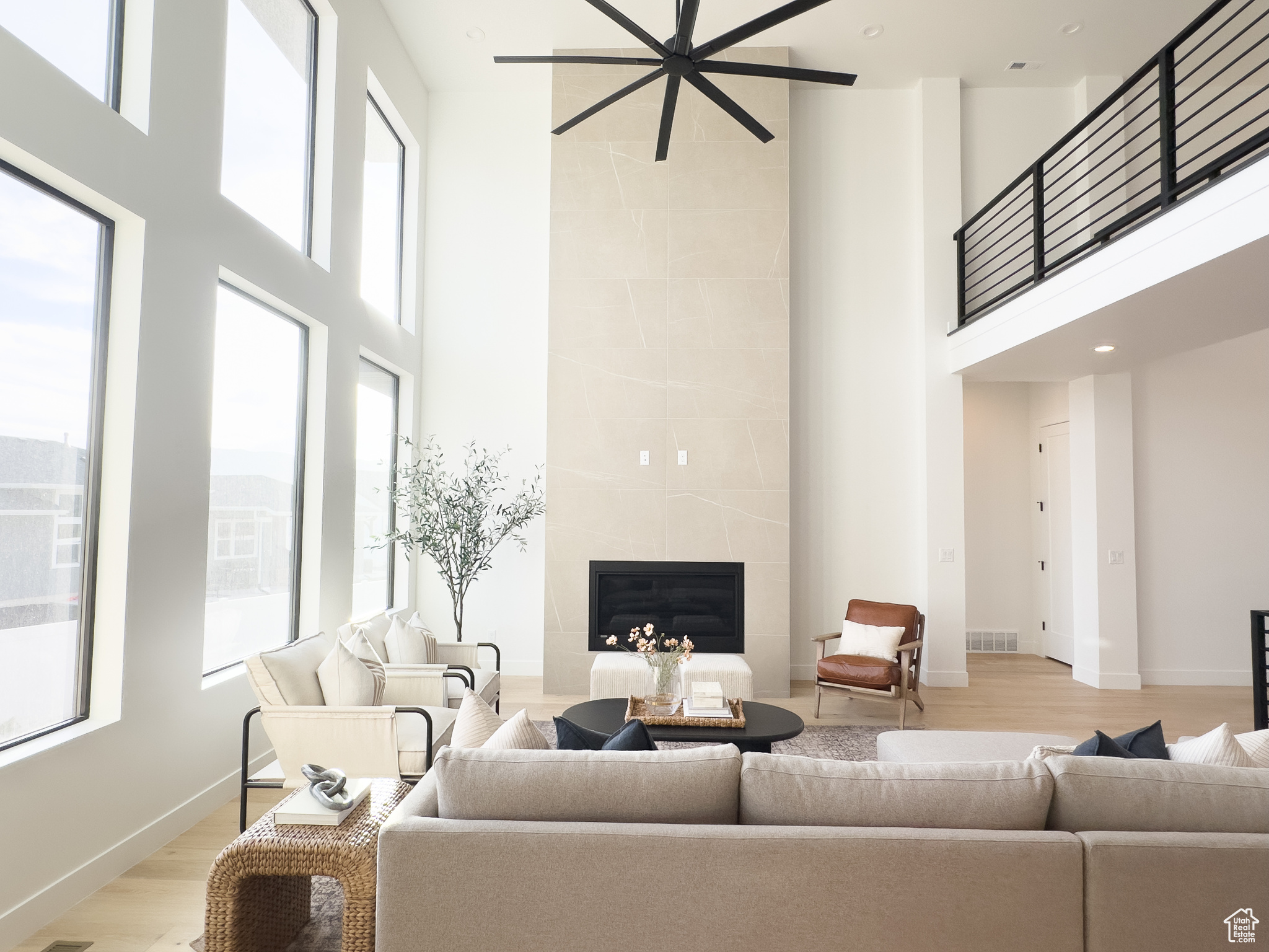 Living room with a tiled fireplace, light hardwood / wood-style flooring, and a towering ceiling