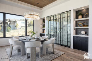 Dining space featuring ornamental molding, hardwood / wood-style floors, wood ceiling, and an inviting chandelier