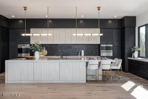 Kitchen featuring light wood-type flooring, hanging light fixtures, and backsplash