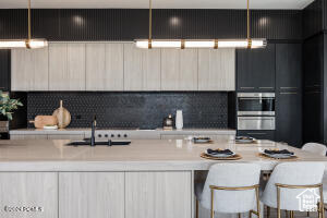 Kitchen featuring sink, stainless steel double oven, tasteful backsplash, and a kitchen breakfast bar