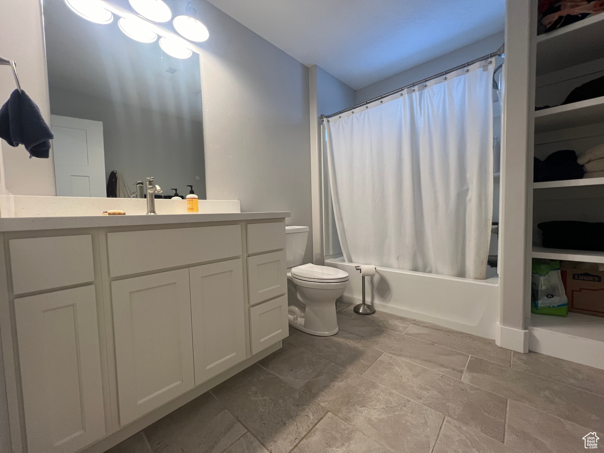Full bathroom featuring toilet, vanity, tile flooring, and shower / bath combo with shower curtain