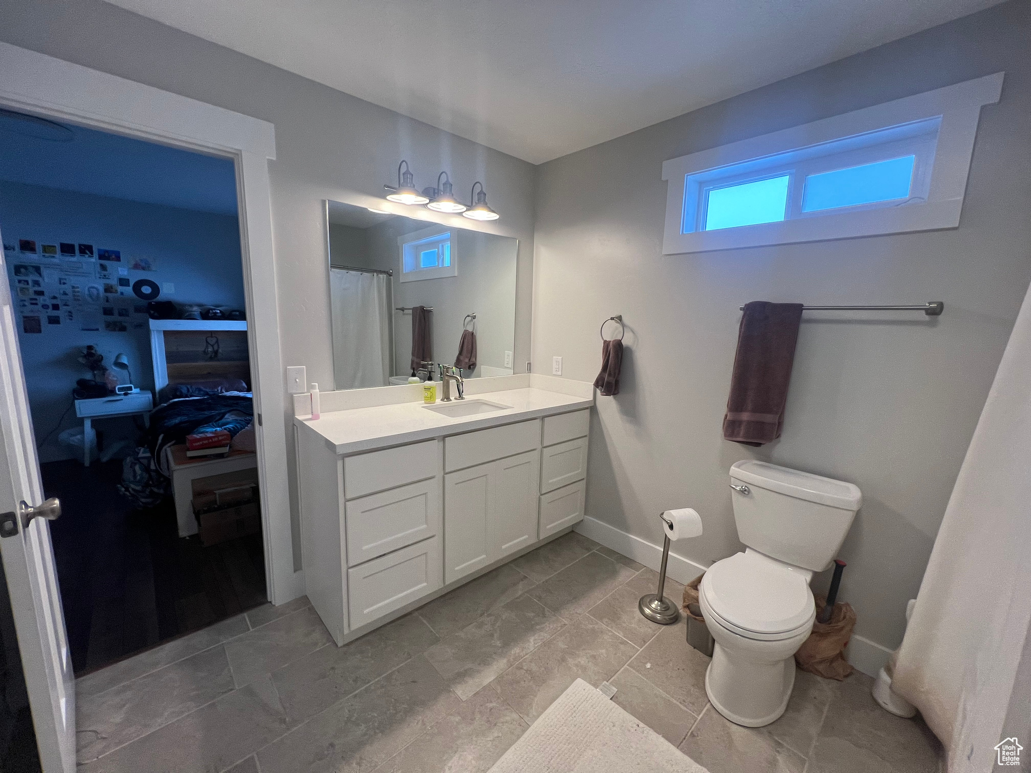 Bathroom with vanity with extensive cabinet space, tile floors, and toilet