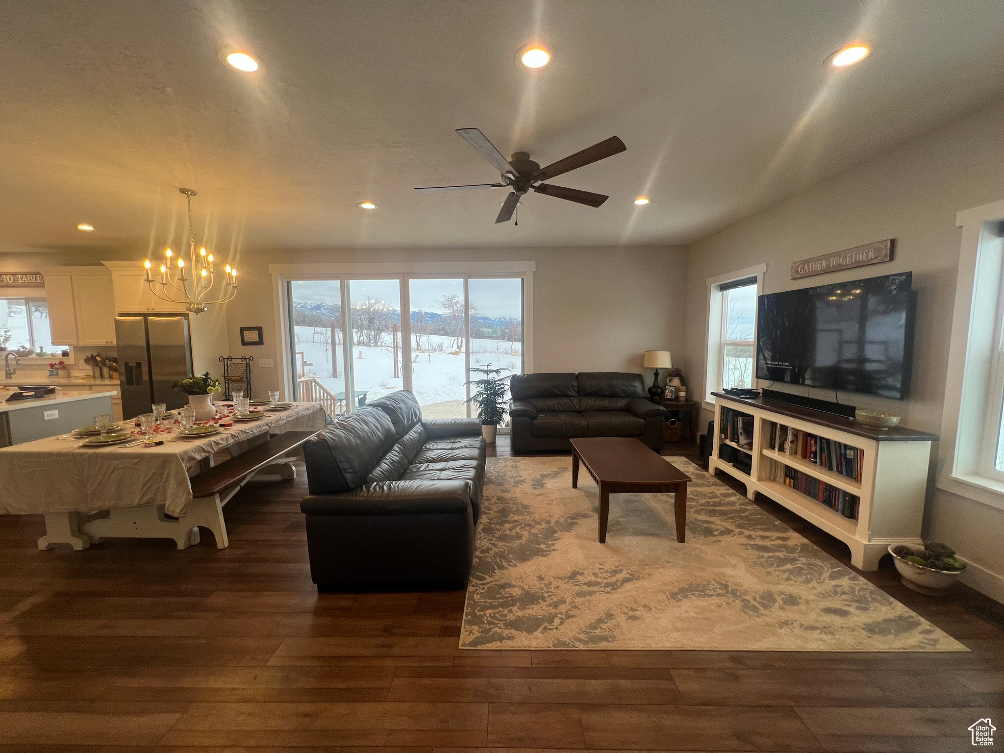 Living room featuring a wealth of natural light, dark hardwood / wood-style flooring, ceiling fan with notable chandelier, and sink