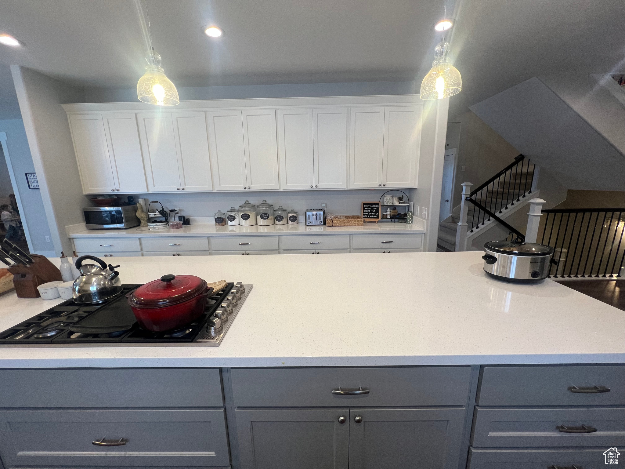 Kitchen featuring pendant lighting, gray cabinets, black gas stovetop, and white cabinetry