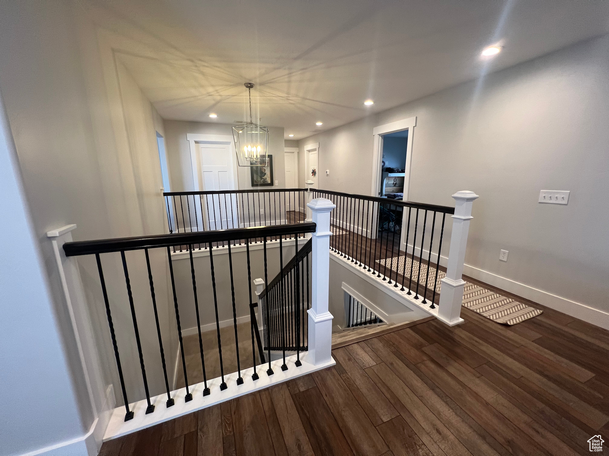 Stairway featuring an inviting chandelier and dark hardwood / wood-style flooring