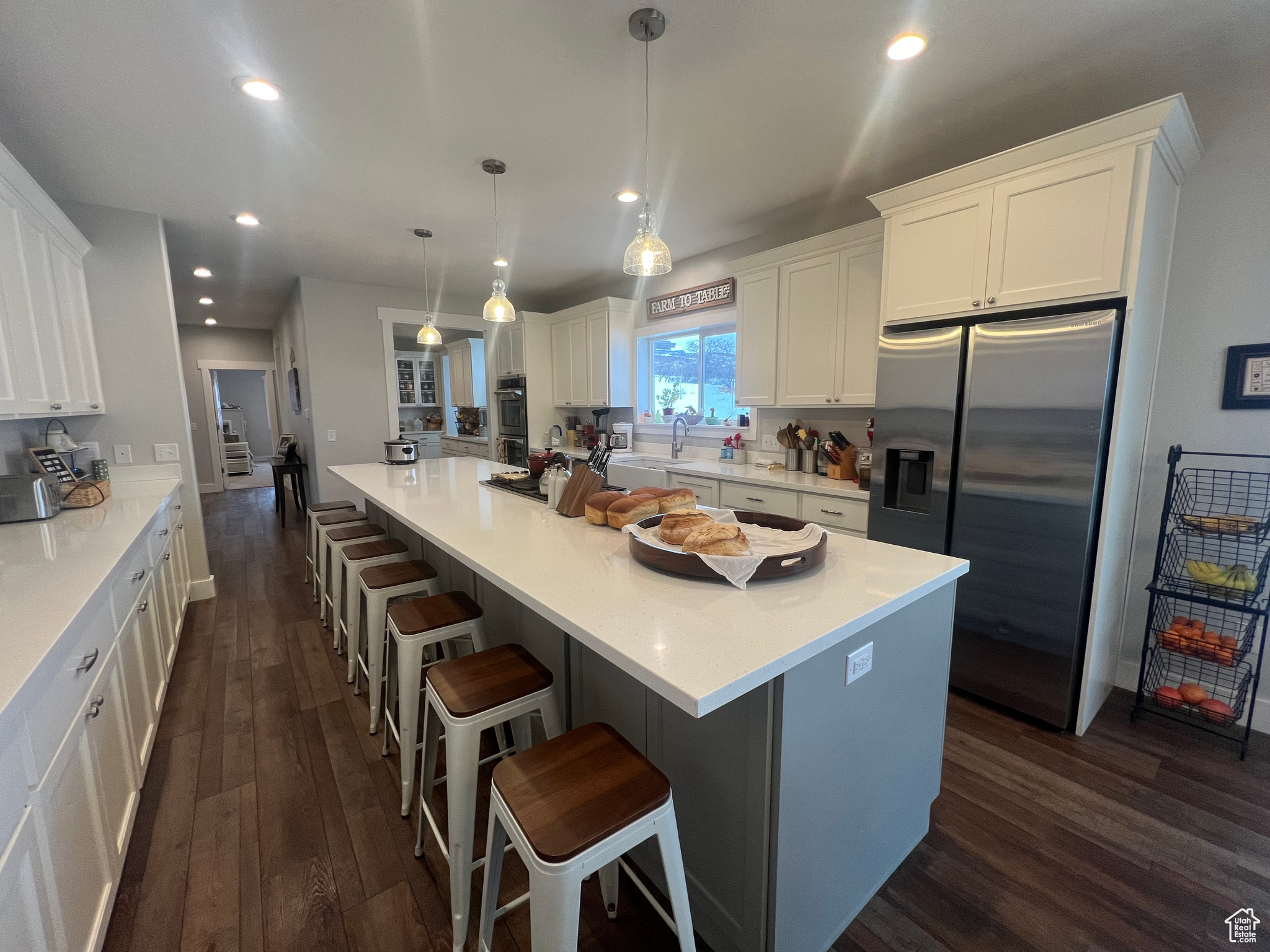 Kitchen featuring hanging light fixtures, appliances with stainless steel finishes, dark wood-type flooring, and white cabinets