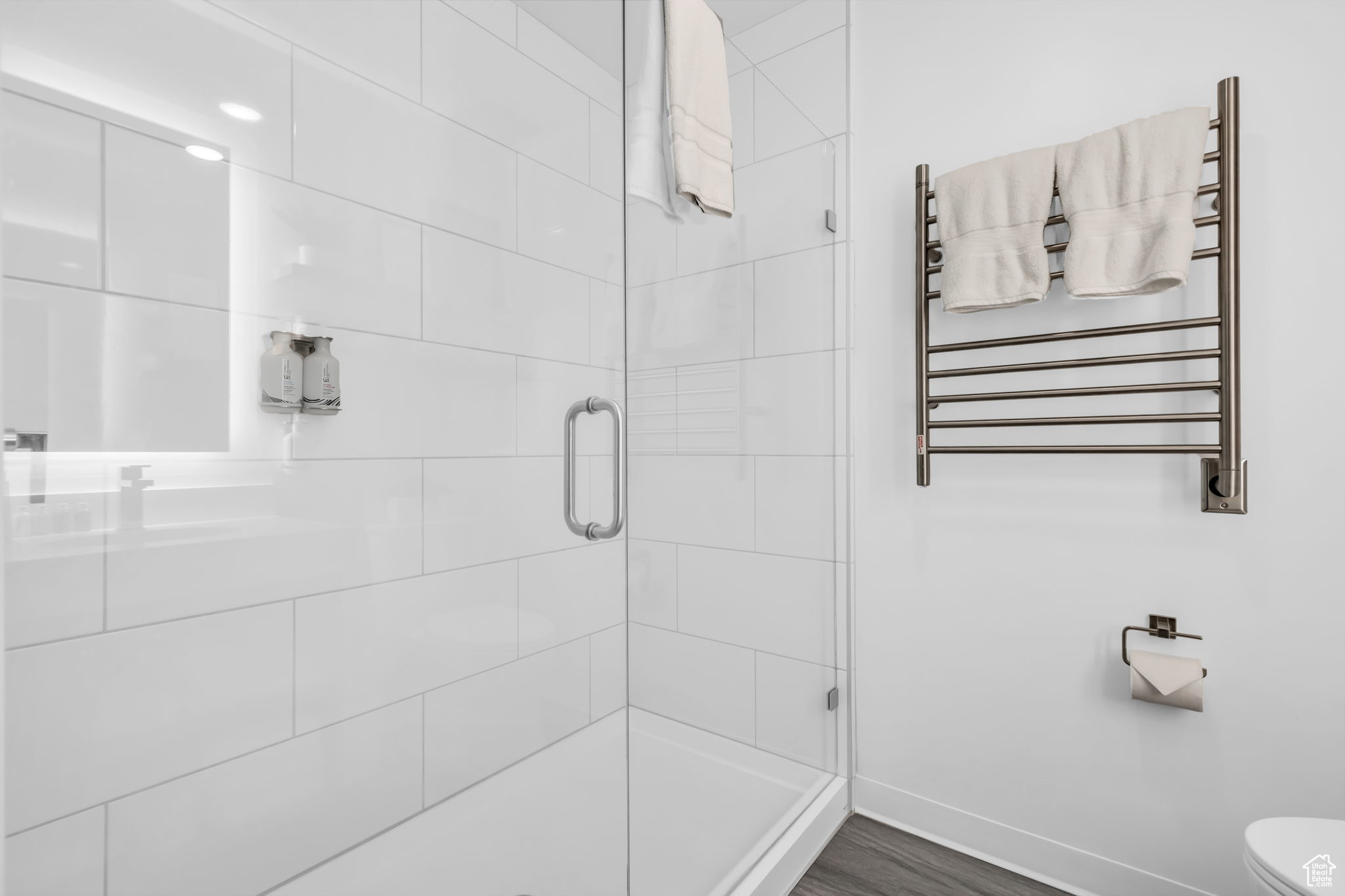Bathroom with toilet, hardwood / wood-style floors, an enclosed shower, and radiator heating unit