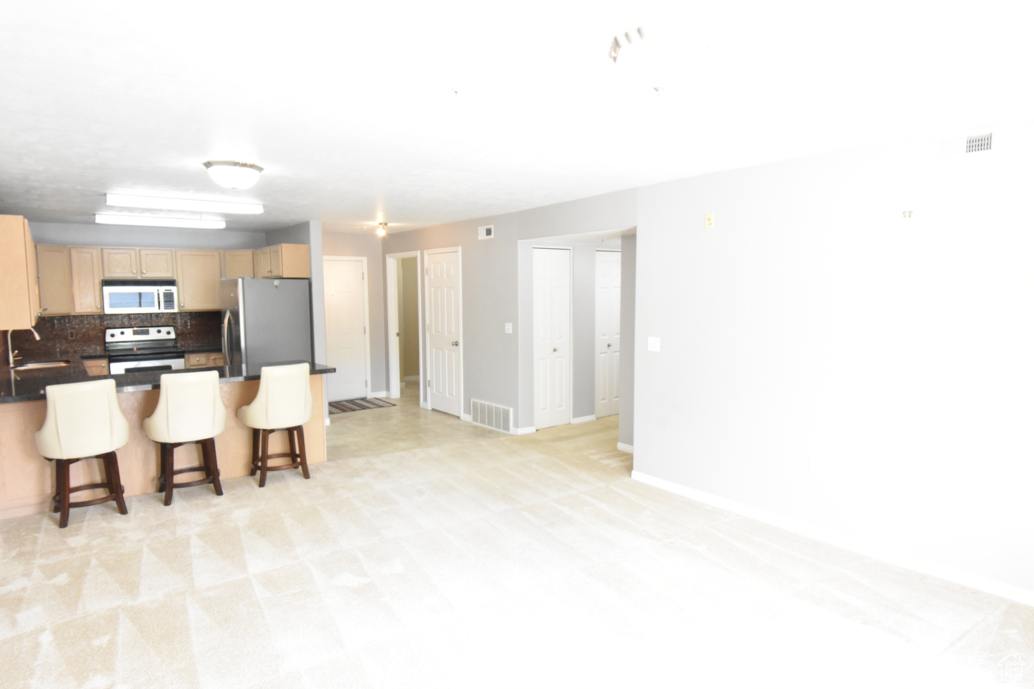 Kitchen with stainless steel appliances, a breakfast bar, sink, tasteful backsplash, and light tile floors