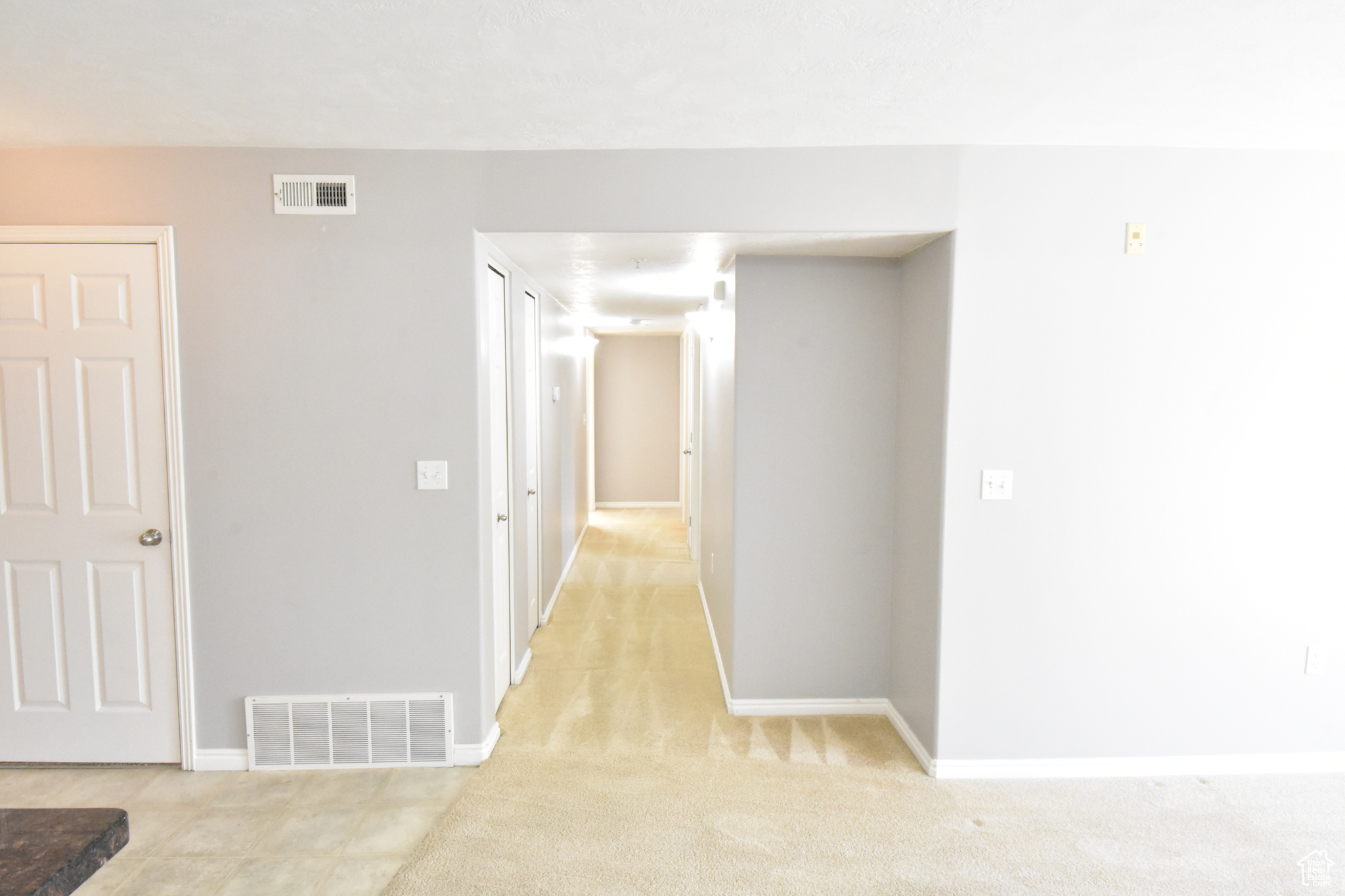 Hallway featuring light colored carpet