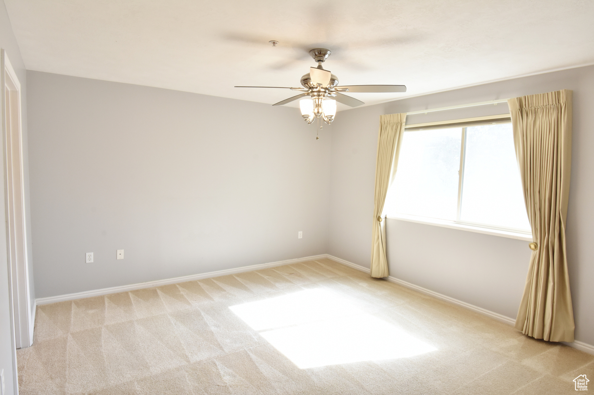 Spare room with ceiling fan and light colored carpet