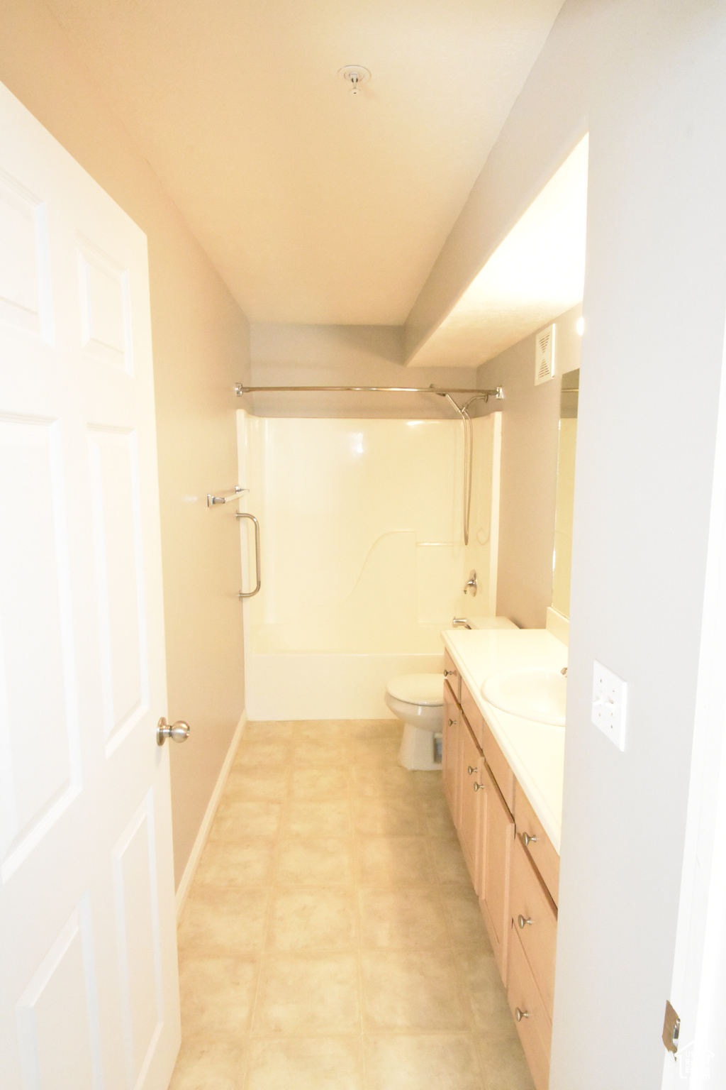 Full bathroom with tile floors, enclosed tub / shower combo, toilet, and vanity