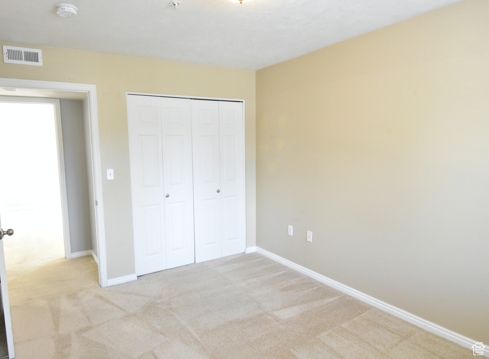 Unfurnished bedroom featuring a closet and light colored carpet