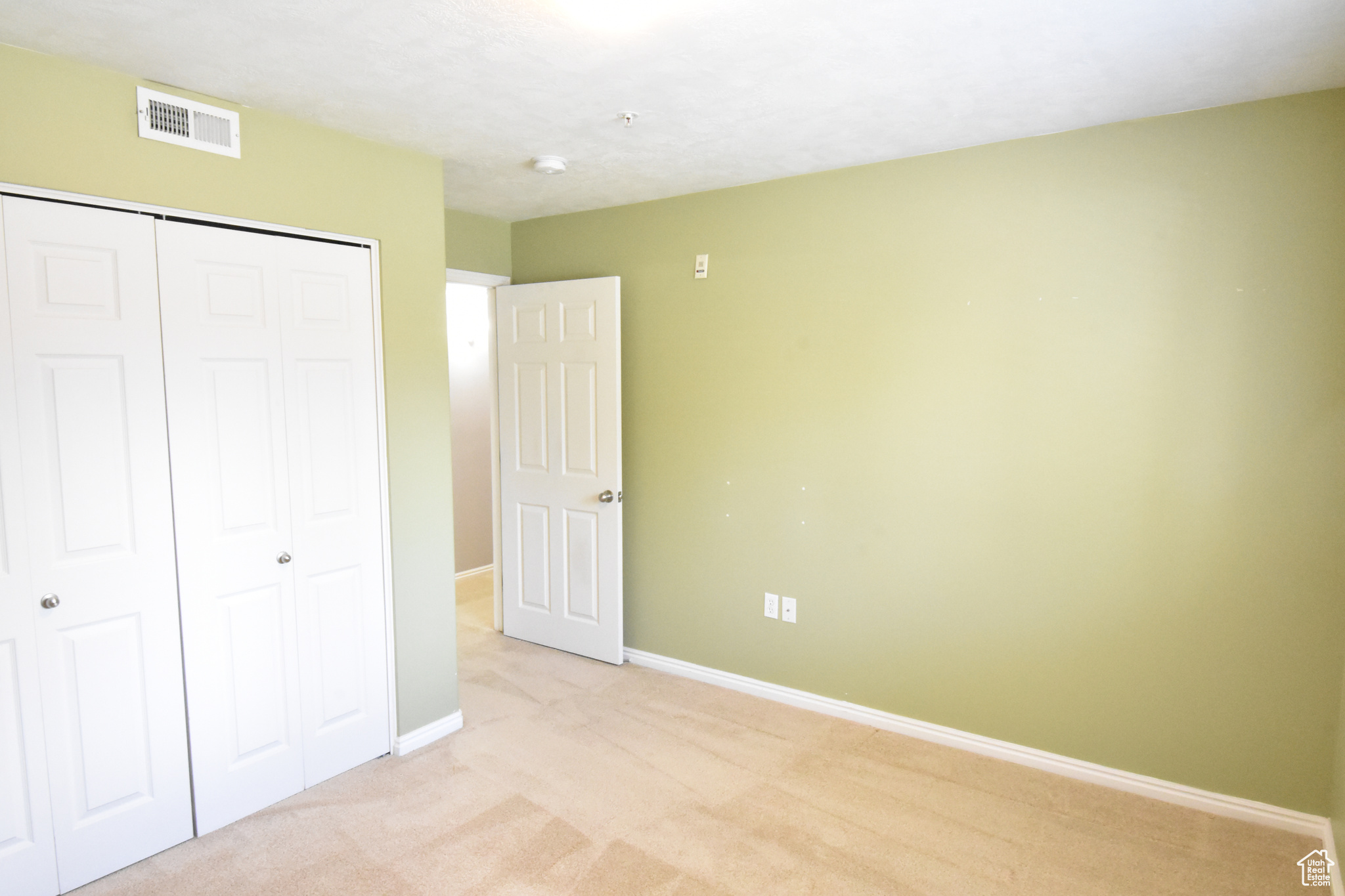 Unfurnished bedroom with light carpet and a closet