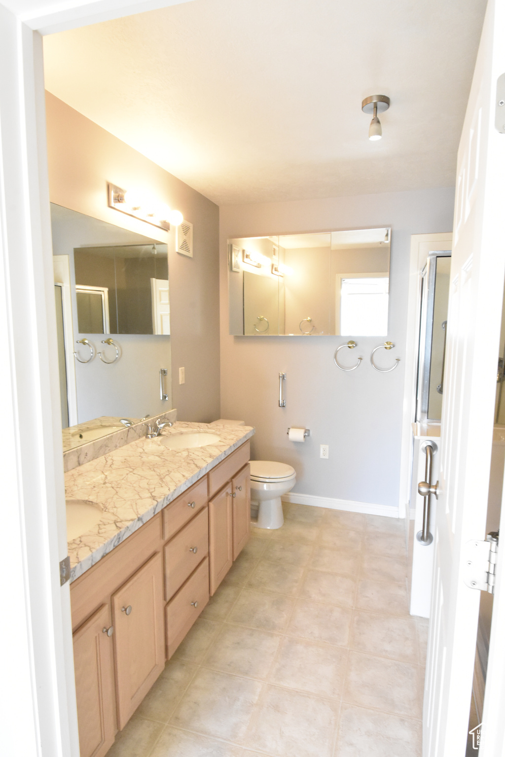 Bathroom featuring dual vanity, toilet, and tile floors