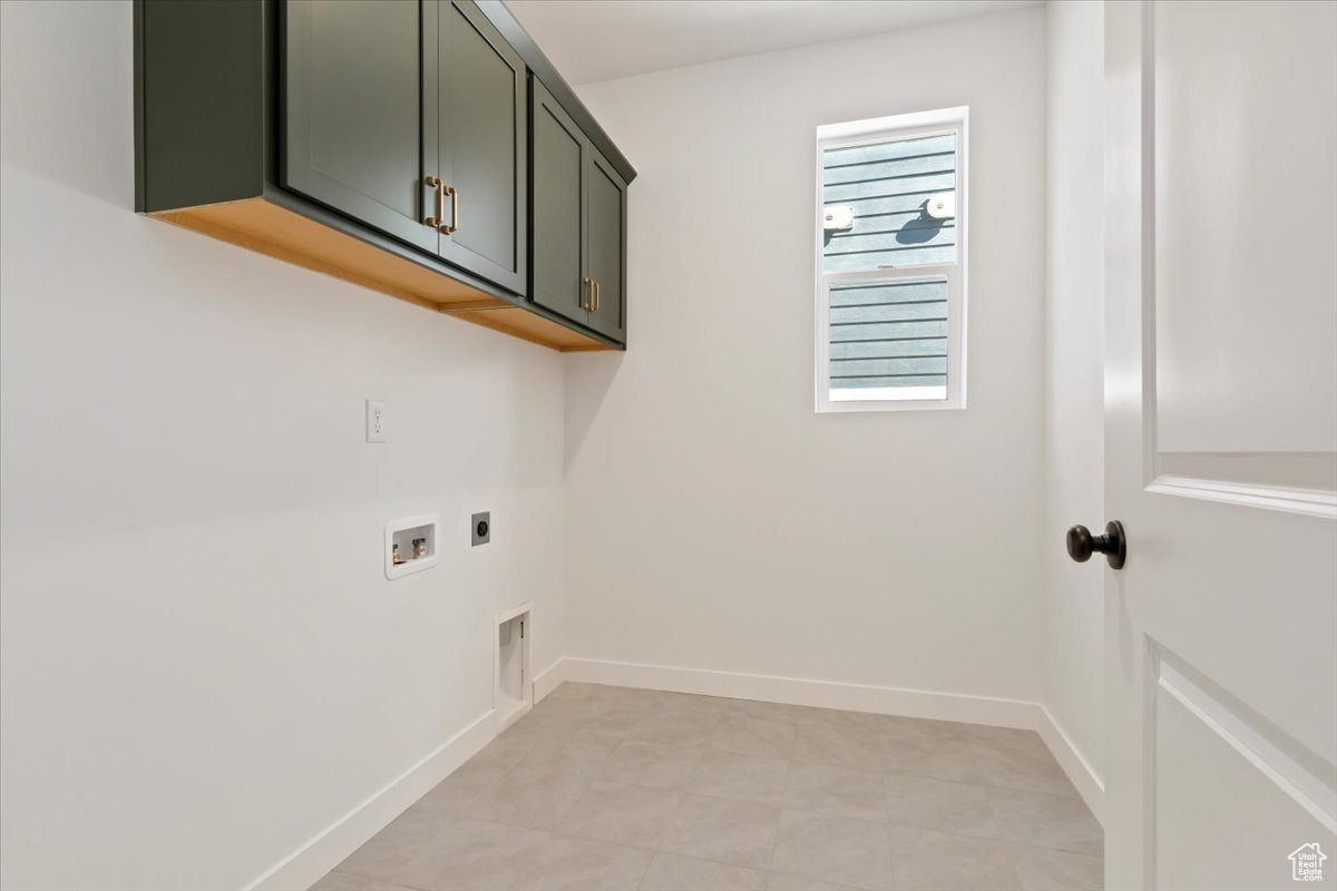 Clothes washing area featuring hookup for a washing machine, electric dryer hookup, cabinets, and light tile flooring