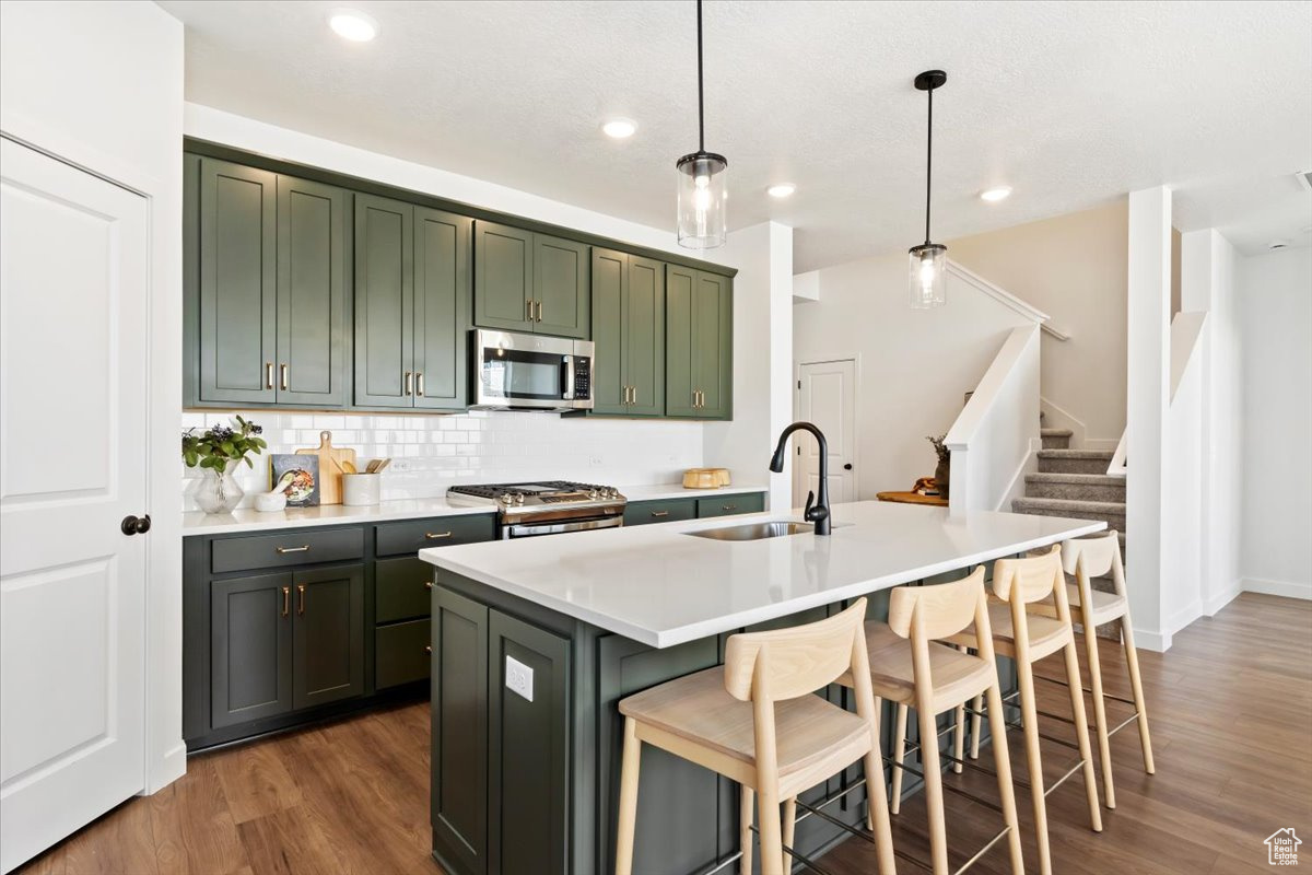 Kitchen with sink, backsplash, decorative light fixtures, dark hardwood / wood-style flooring, and stainless steel appliances