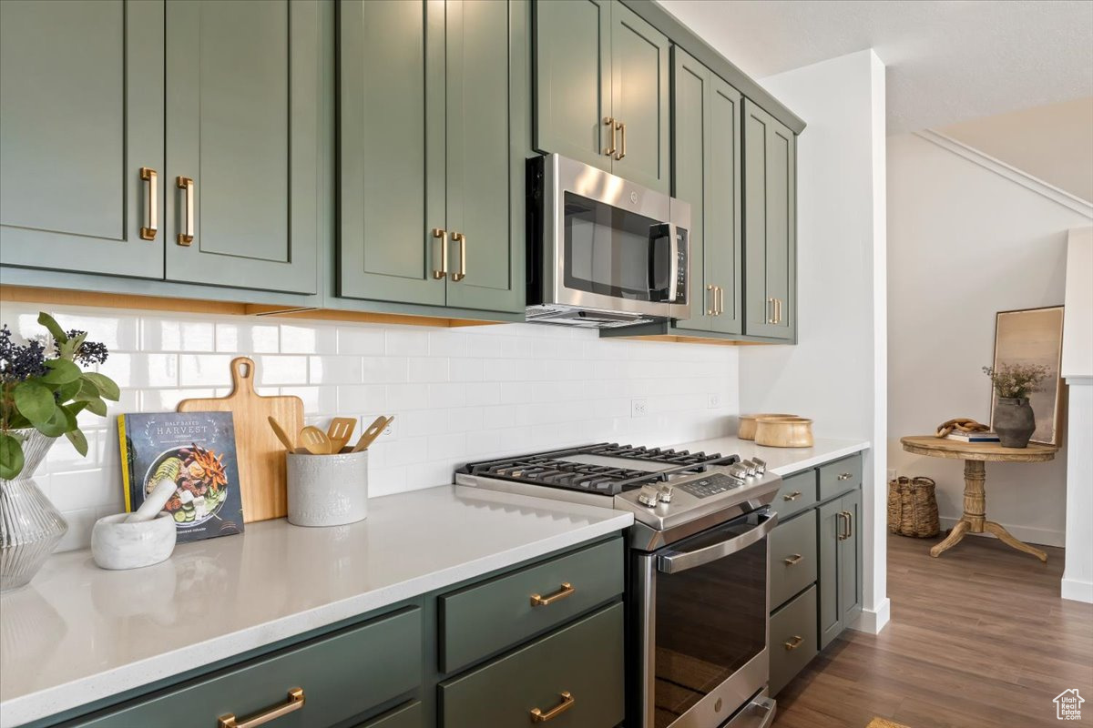 Kitchen featuring backsplash, range with gas stovetop, dark hardwood / wood-style flooring, and green cabinetry