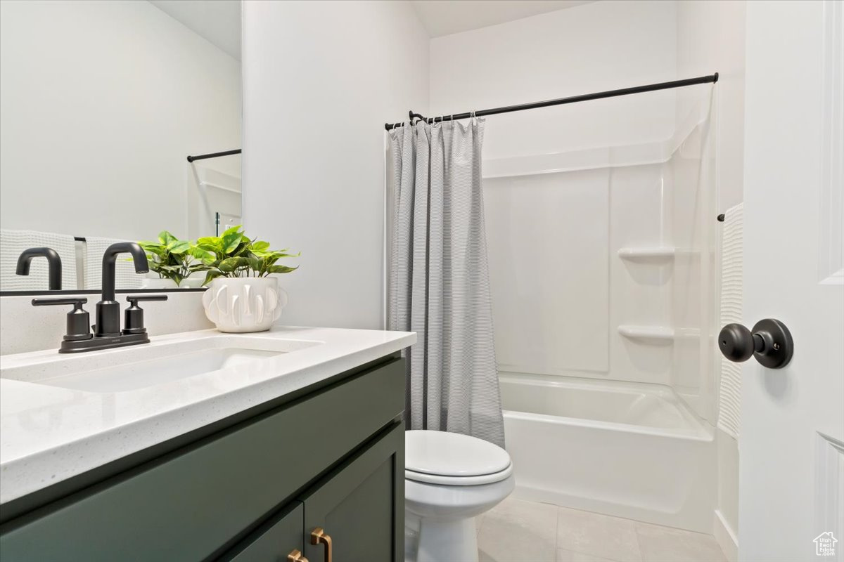 Full bathroom with tile flooring, vanity, toilet, and shower / bath combo with shower curtain