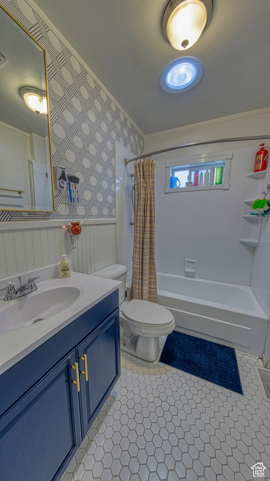 Full bathroom featuring tile floors, shower / bath combination with curtain, oversized vanity, and toilet