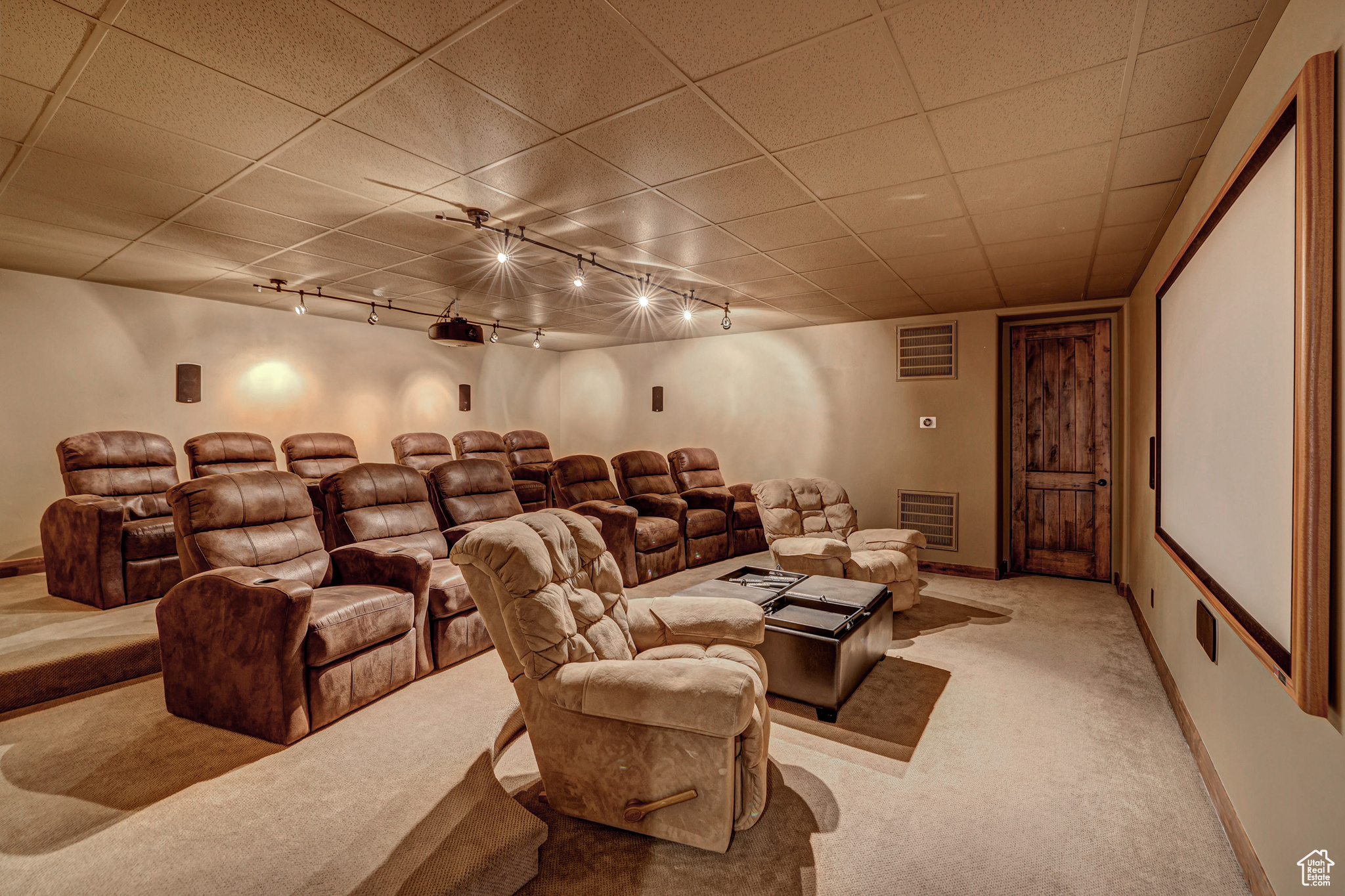 Home theater featuring rail lighting, a paneled ceiling, and light carpet