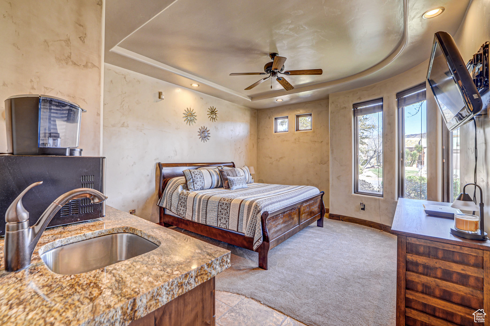 Tiled bedroom with sink, a raised ceiling, and ceiling fan