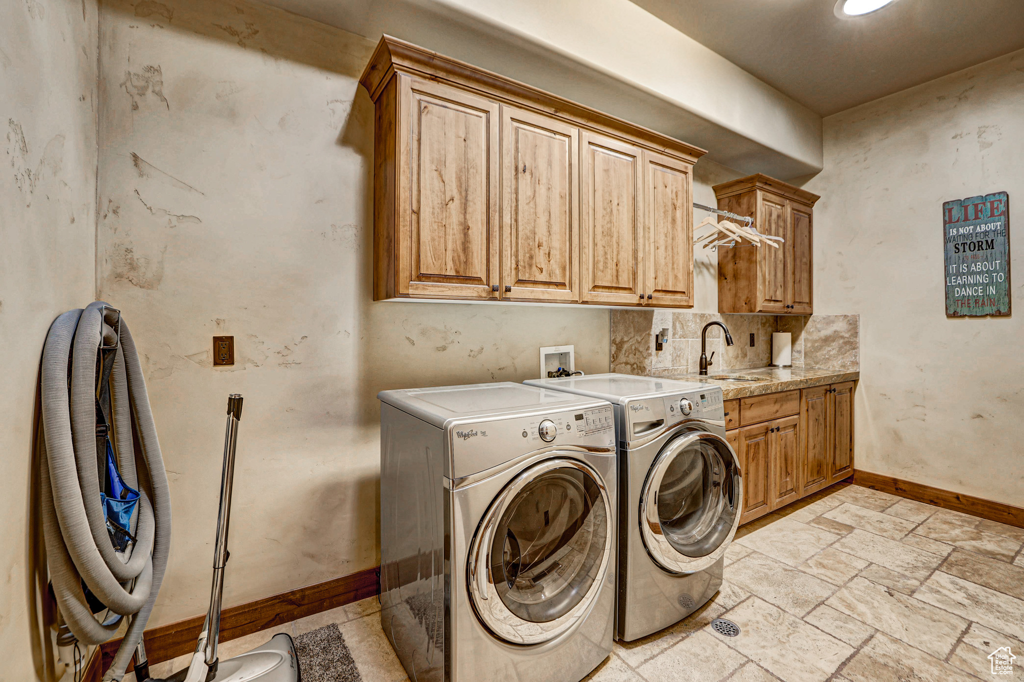 Clothes washing area featuring cabinets, sink, light tile floors, and washing machine and clothes dryer