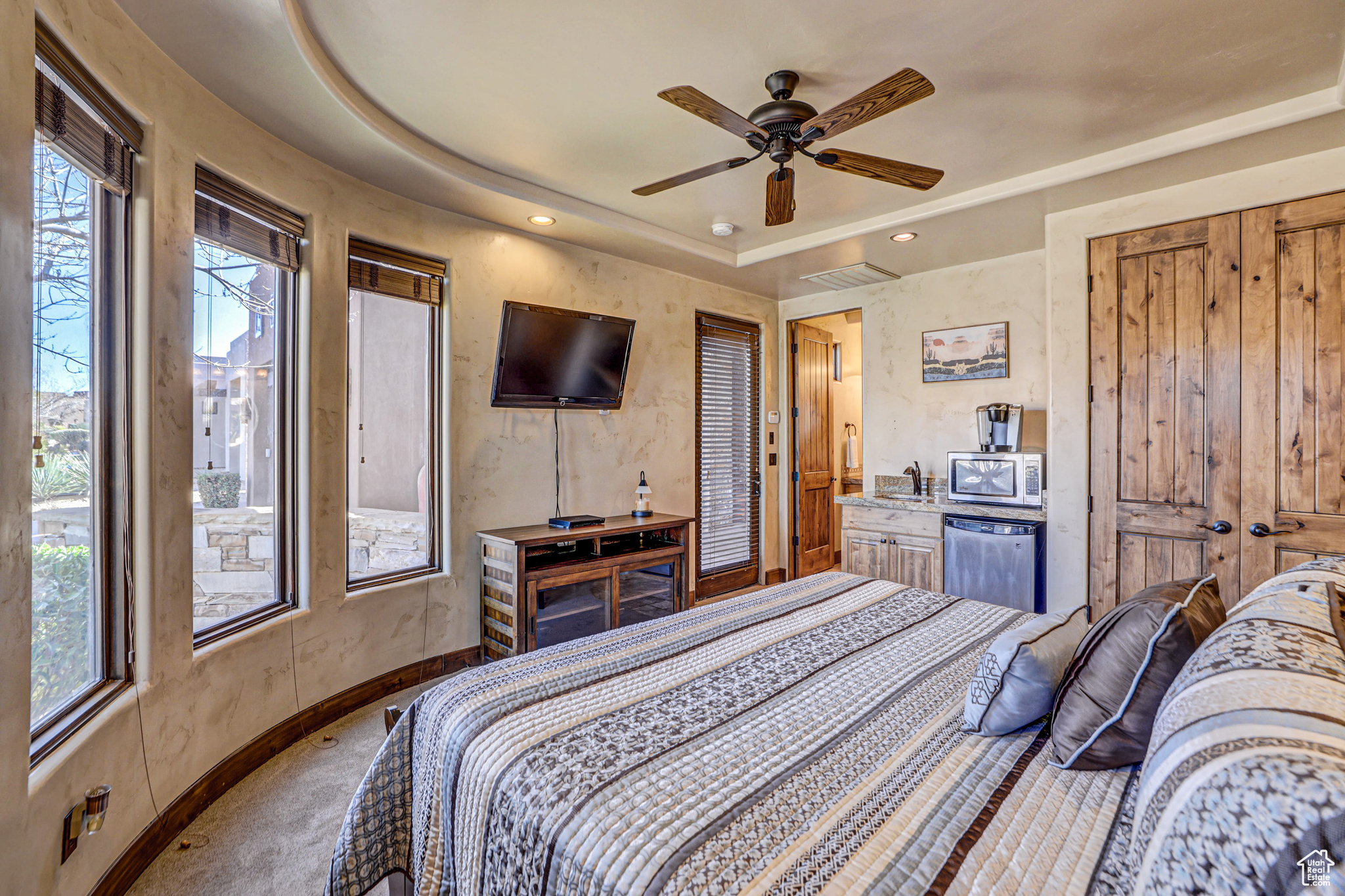 Bedroom featuring multiple windows, carpet floors, a tray ceiling, and ceiling fan