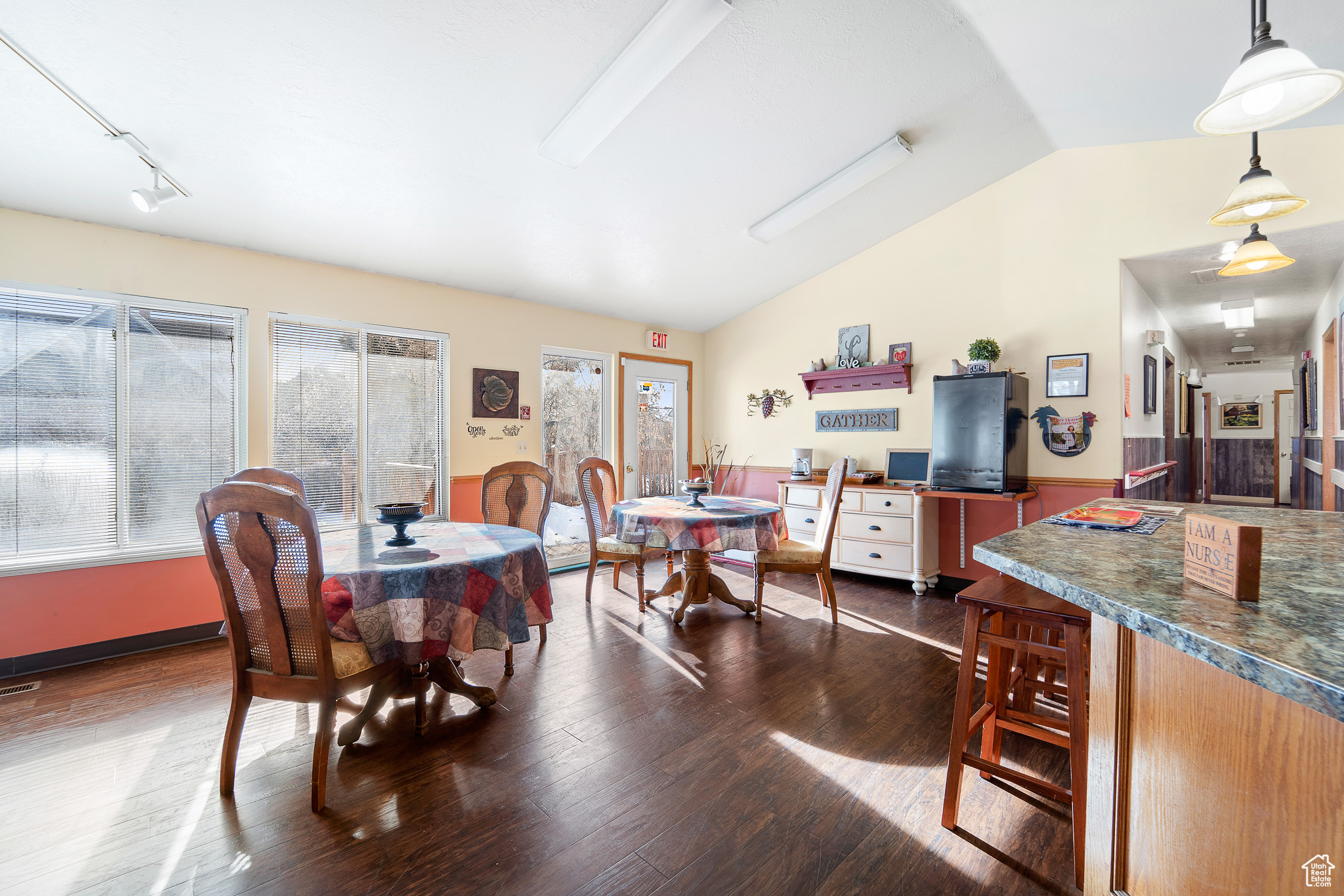 Dining area with dark hardwood / wood-style floors, vaulted ceiling, and track lighting