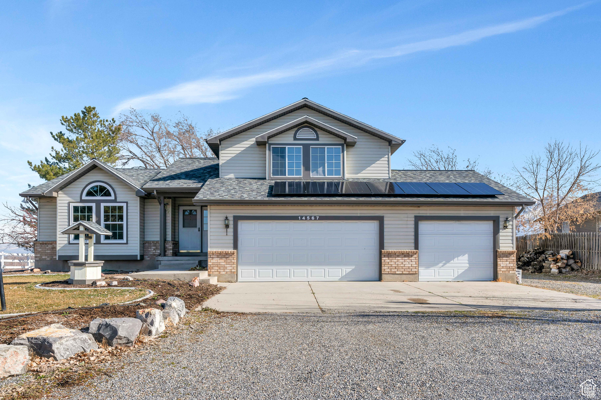 View of front of property featuring solar panels and a garage