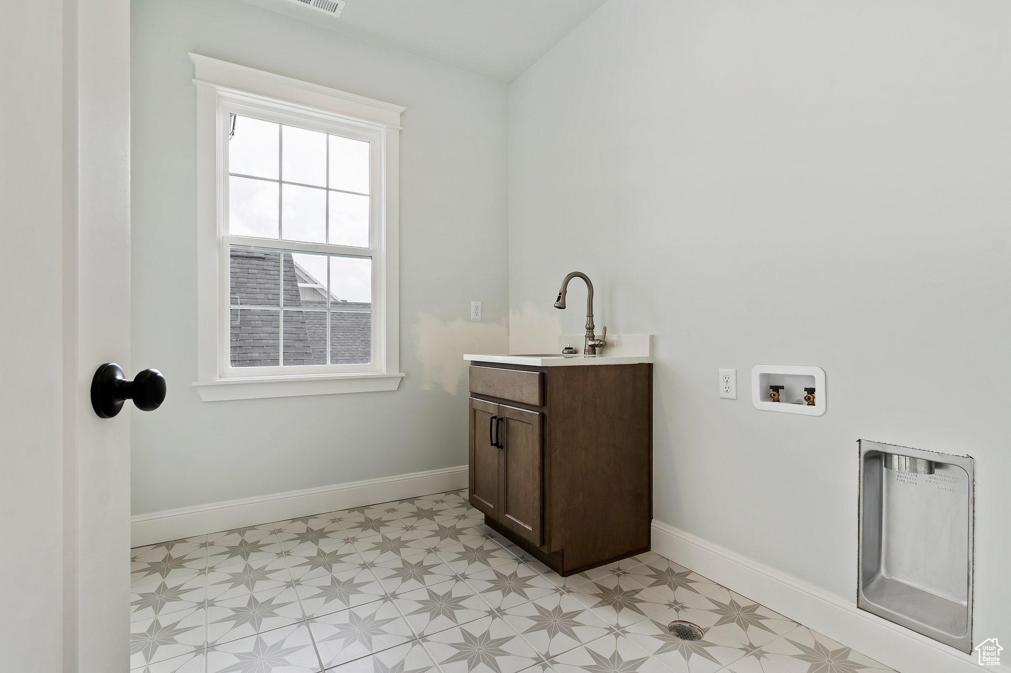 Washroom featuring light tile flooring, cabinets, hookup for a washing machine, and sink