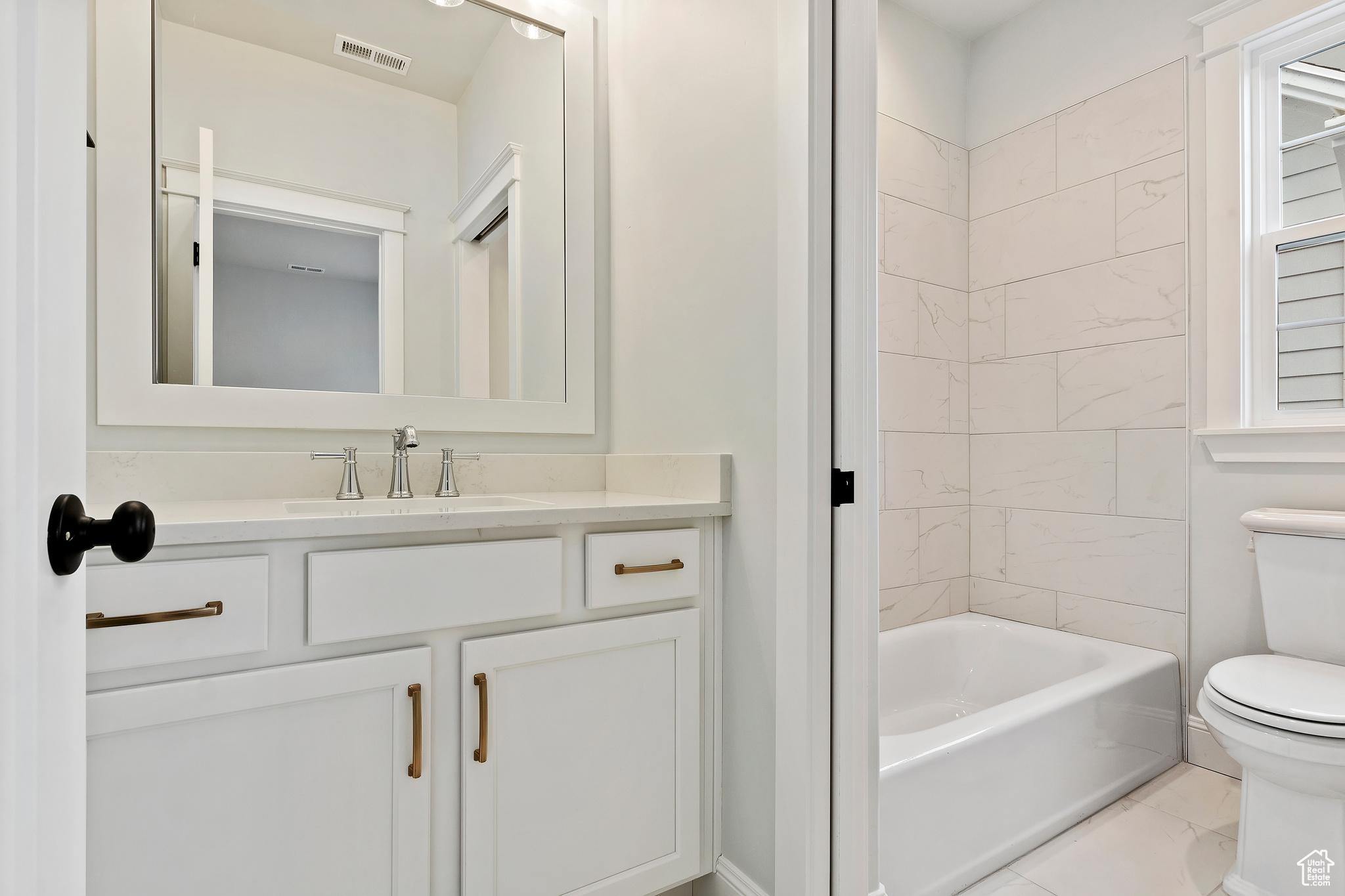 Full bathroom with tile floors, tiled shower / bath, vanity, and toilet