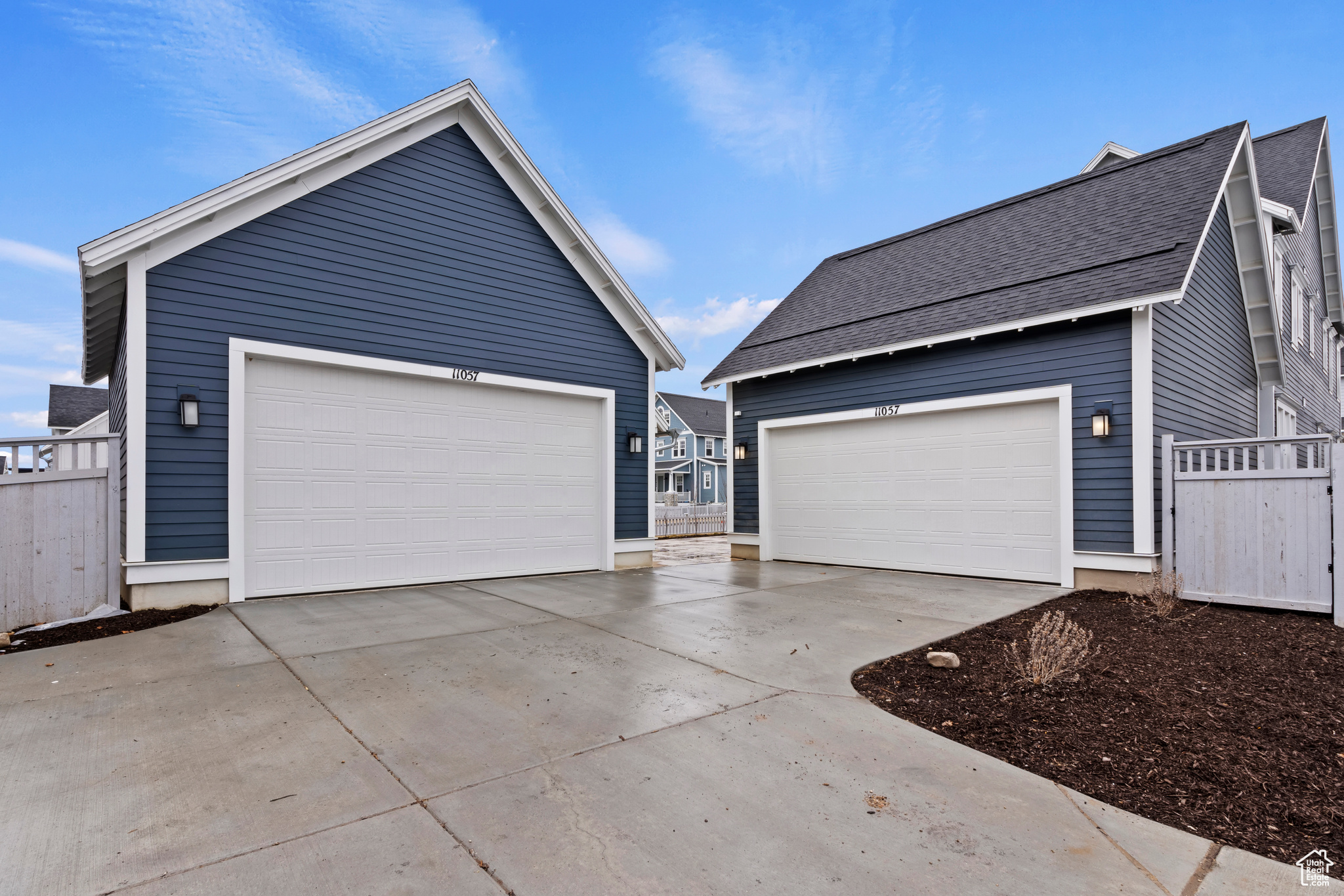 View of driveway featuring both garages and plenty of parking space