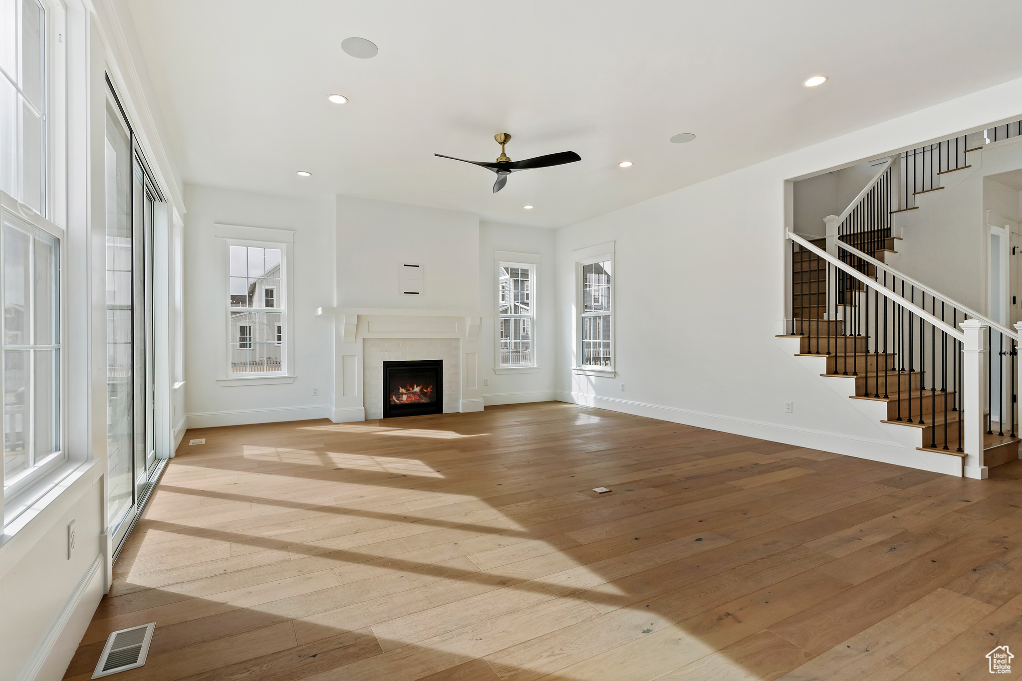 Unfurnished living room with light hardwood / wood-style flooring, ceiling fan, and a healthy amount of sunlight