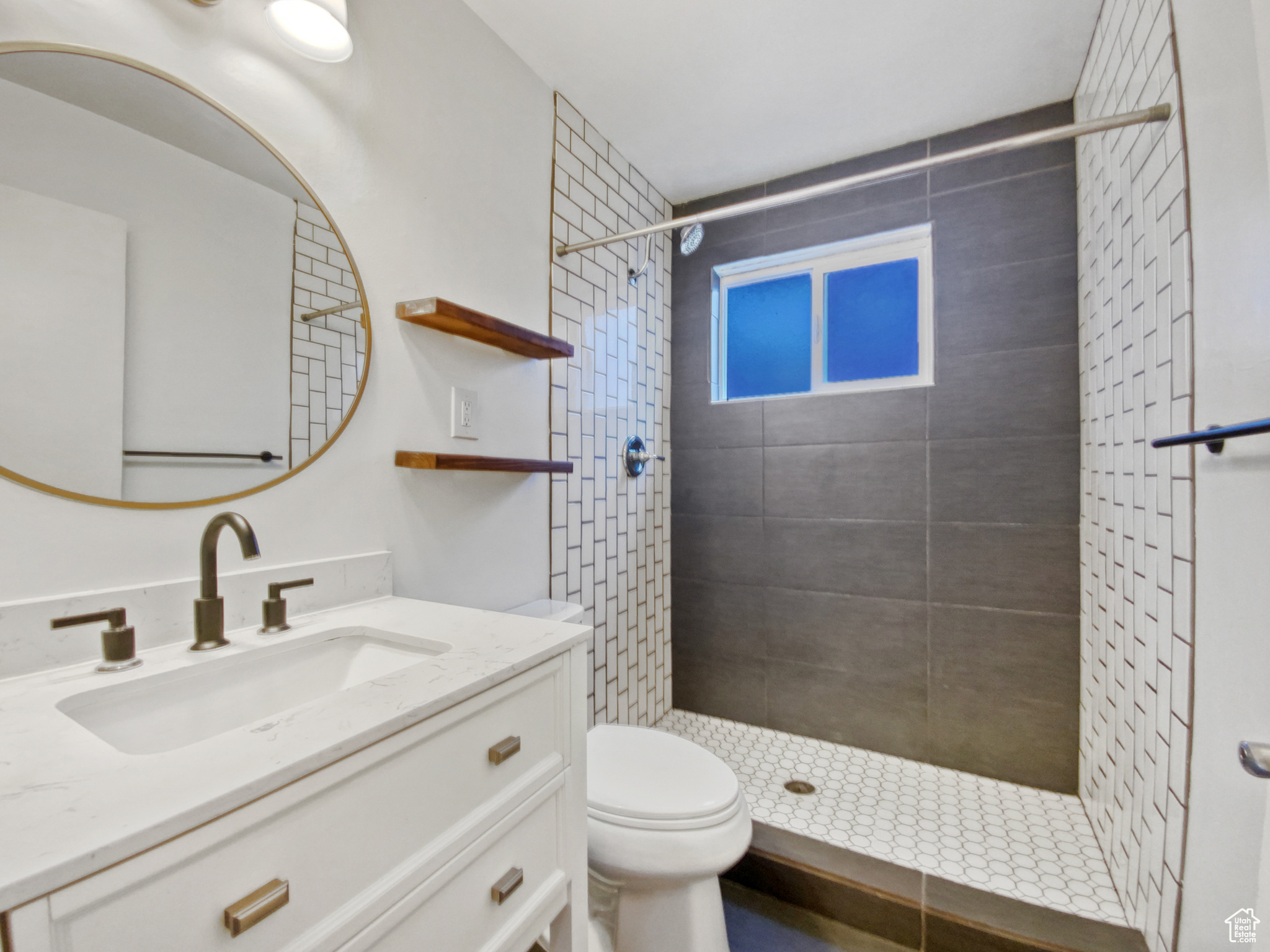 Bathroom with vanity with extensive cabinet space, a tile shower, and toilet