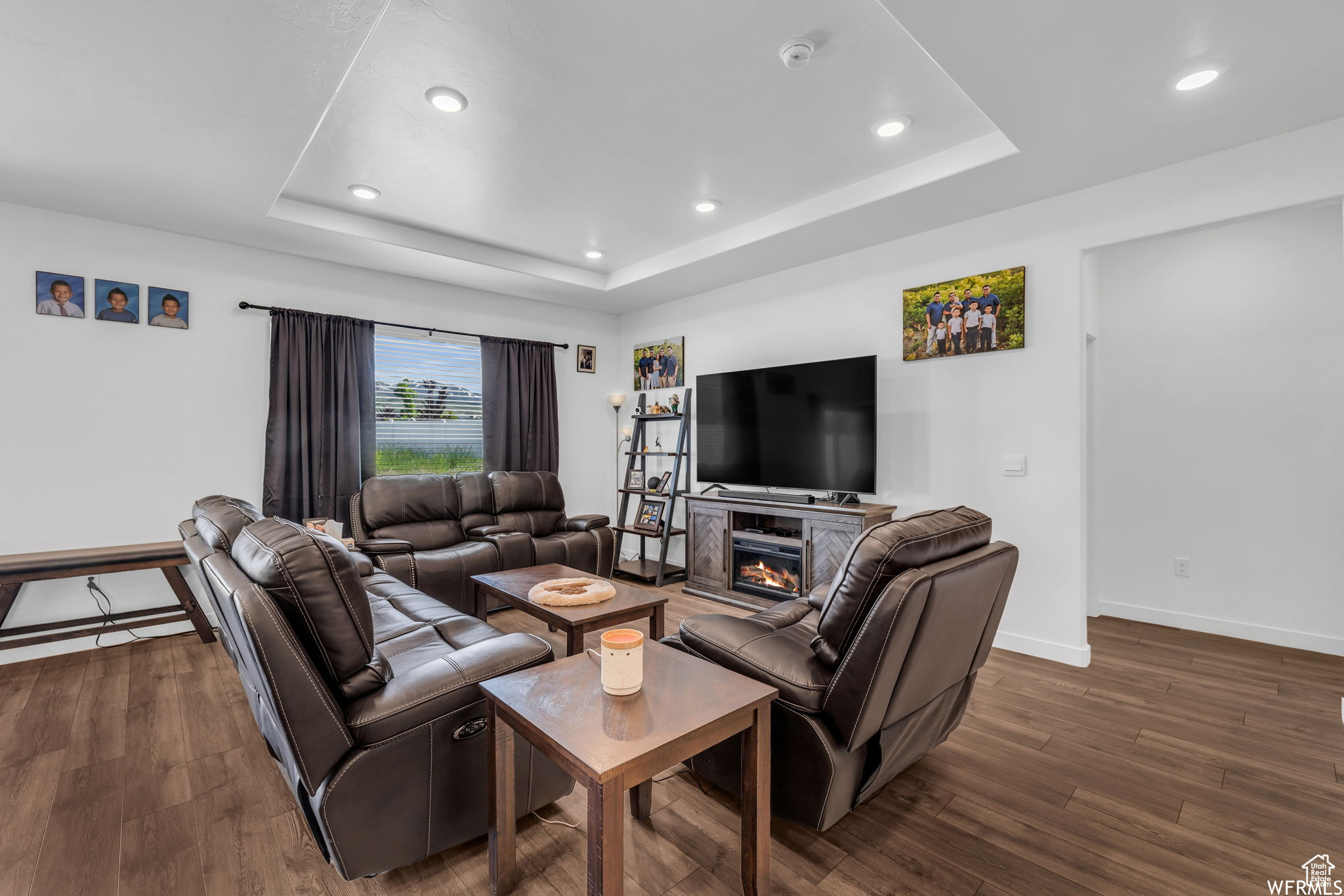 Living room featuring dark wood-type flooring and a tray ceiling