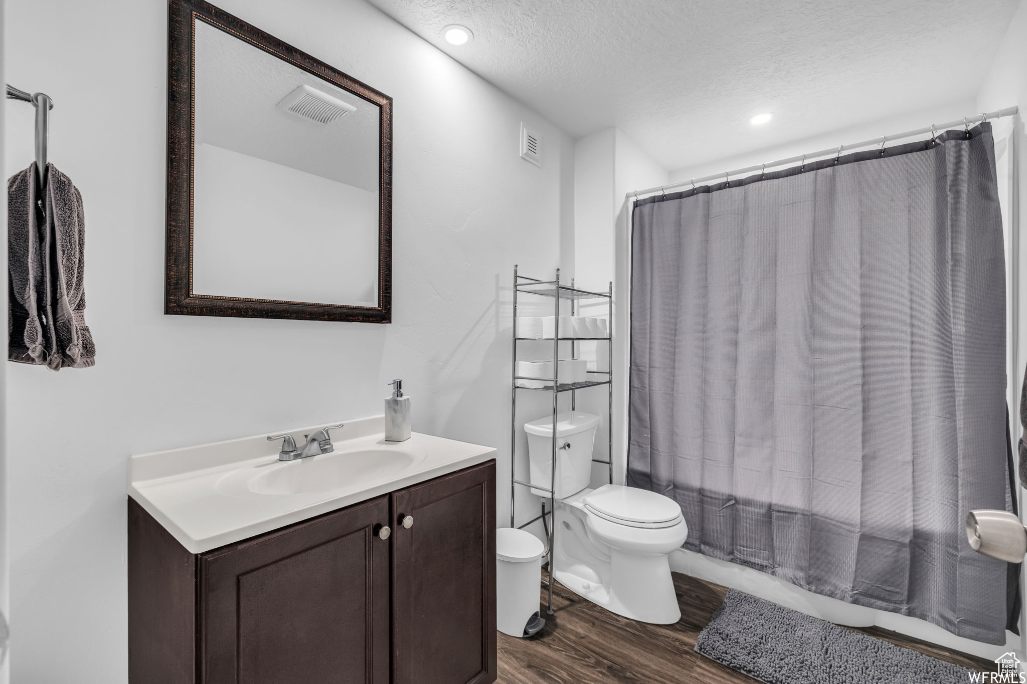 Bathroom featuring toilet, a textured ceiling, oversized vanity, and wood-type flooring