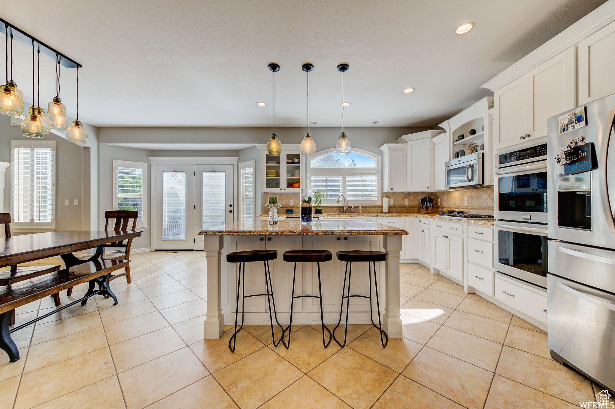 Kitchen featuring white cabinets, a kitchen island, stainless steel appliances, and decorative light fixtures