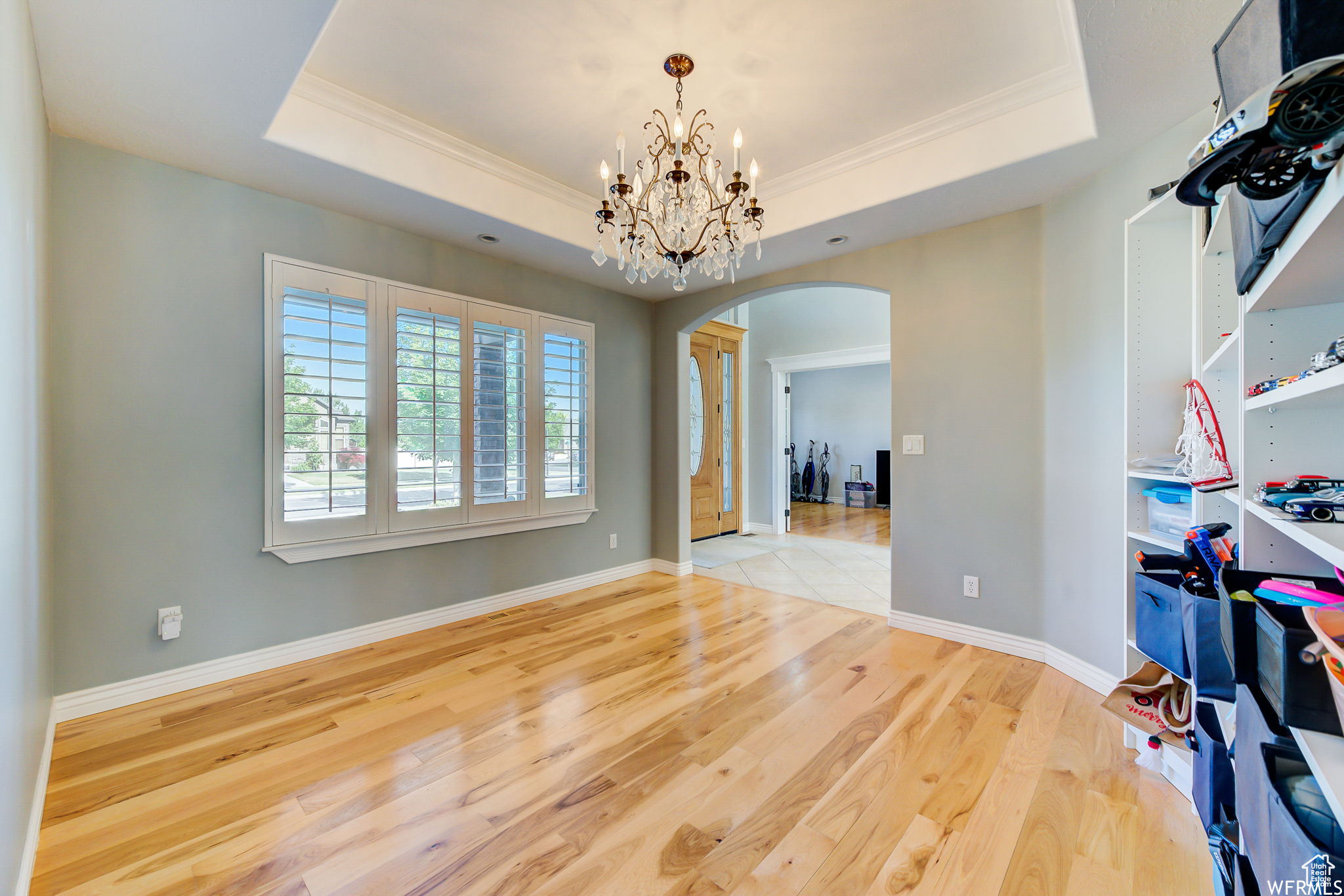 Interior space featuring a notable chandelier, light tile floors, crown molding, and a raised ceiling