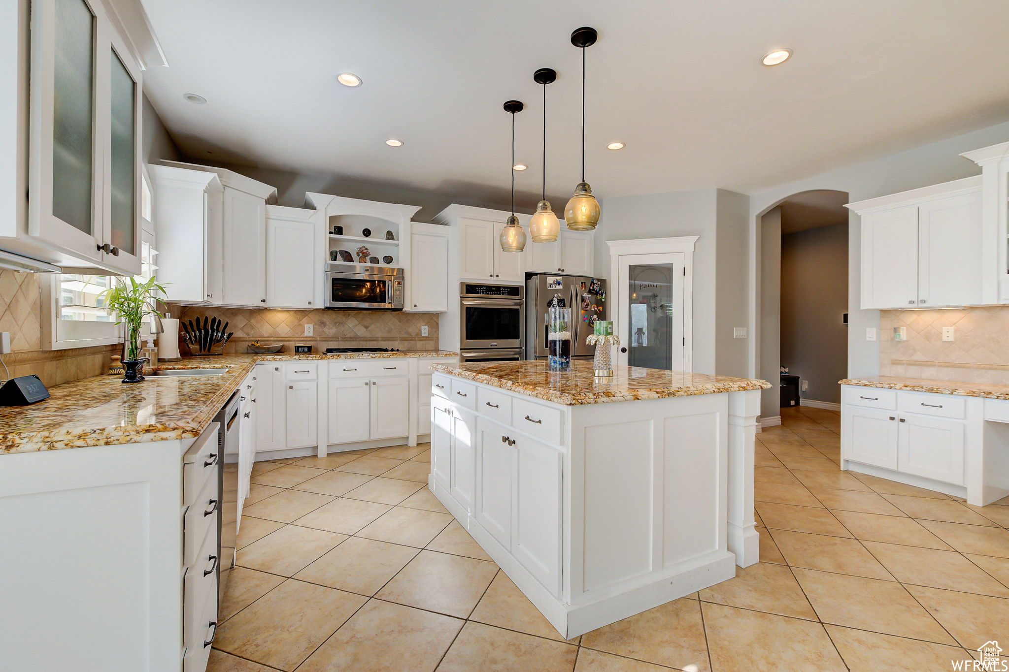 Kitchen featuring pendant lighting, white cabinets, tasteful backsplash, appliances with stainless steel finishes, and a center island