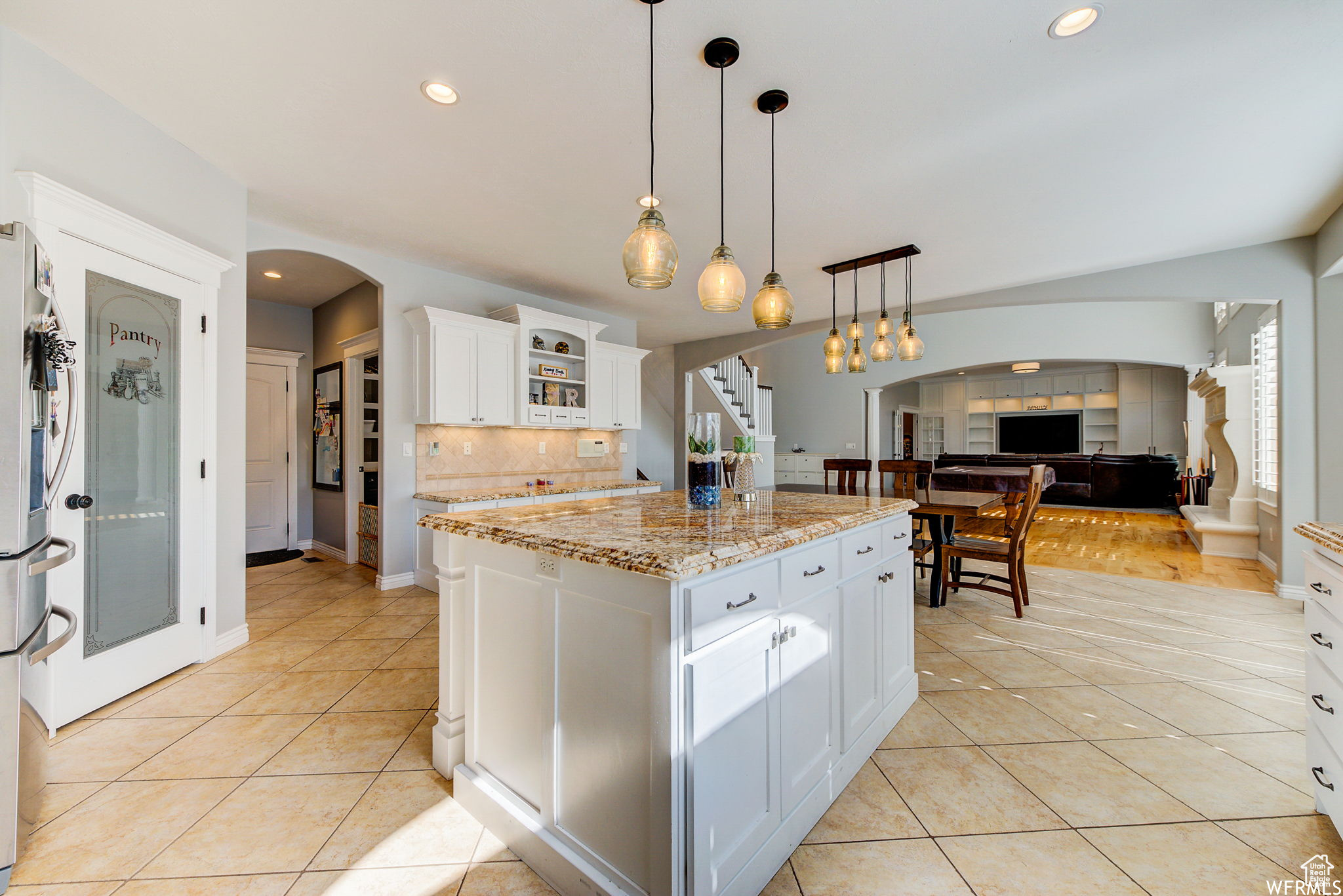 Kitchen featuring a kitchen island, hanging light fixtures, backsplash, and white cabinetry