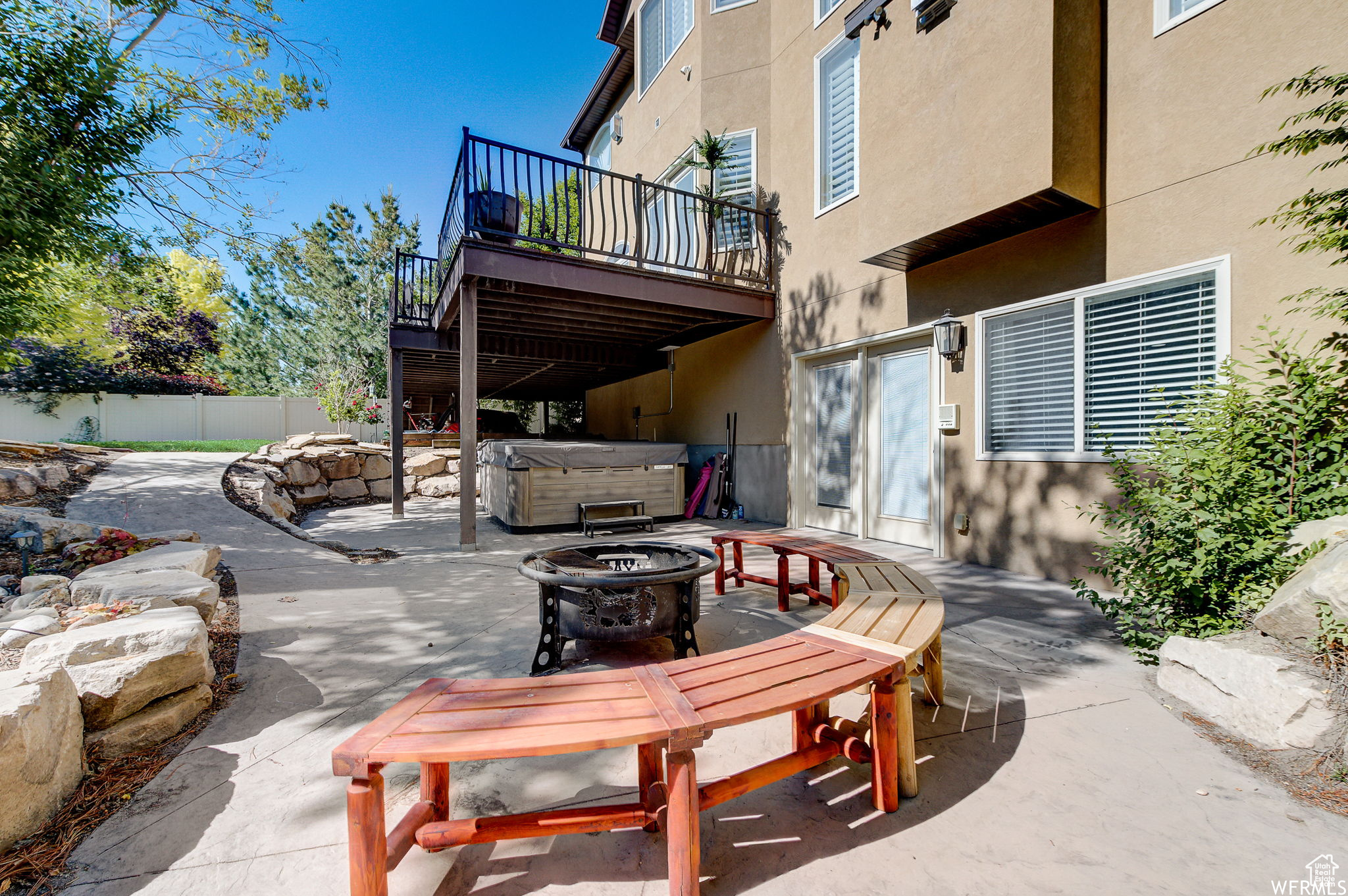 View of terrace with a hot tub, a wooden deck, and a fire pit