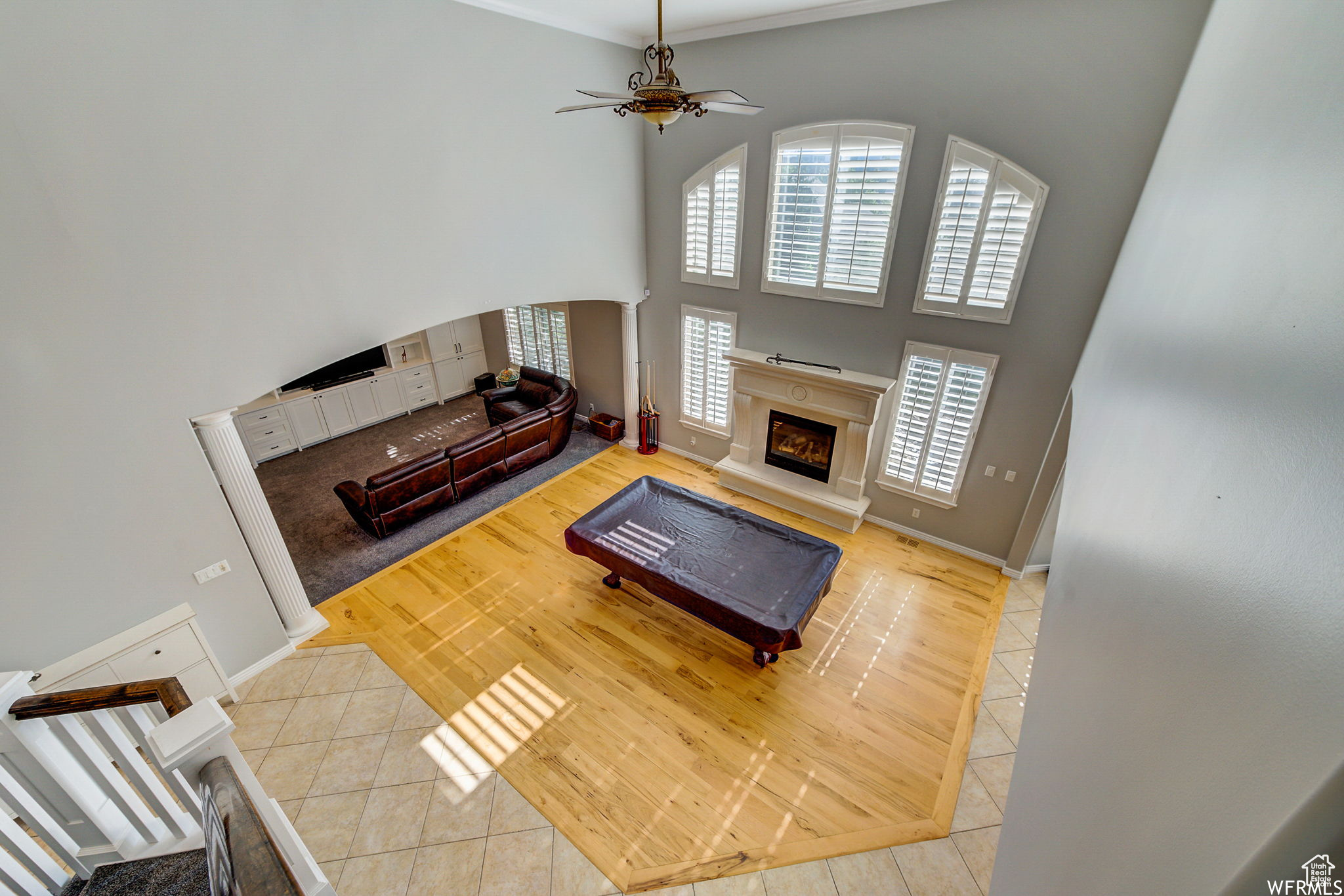 Living room featuring light hardwood / wood-style floors, crown molding, a towering ceiling, and ceiling fan