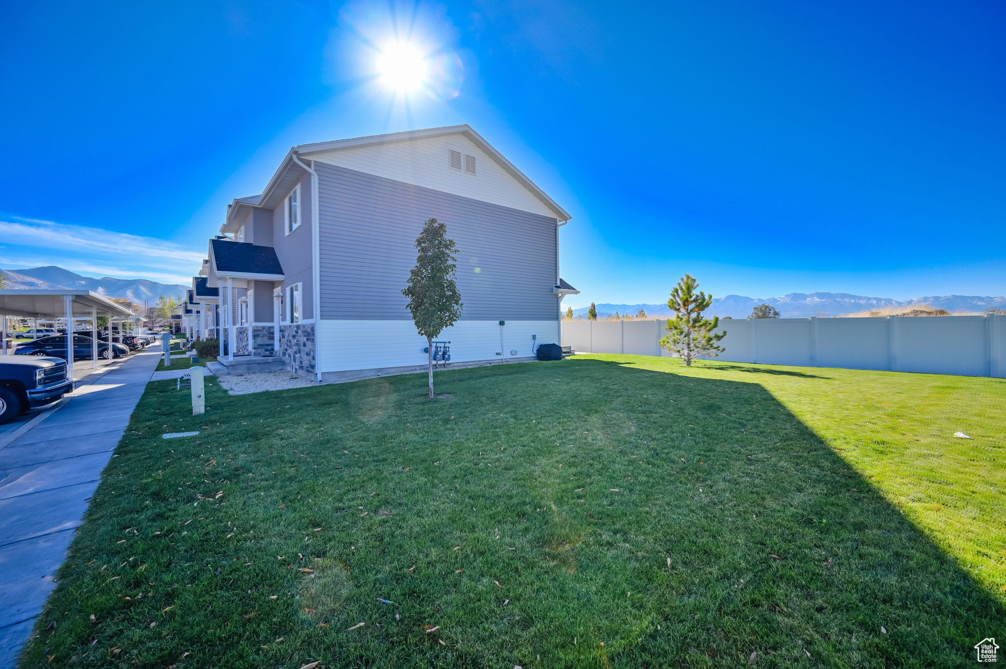 Side view of property with a carport, a lawn, and a mountain view